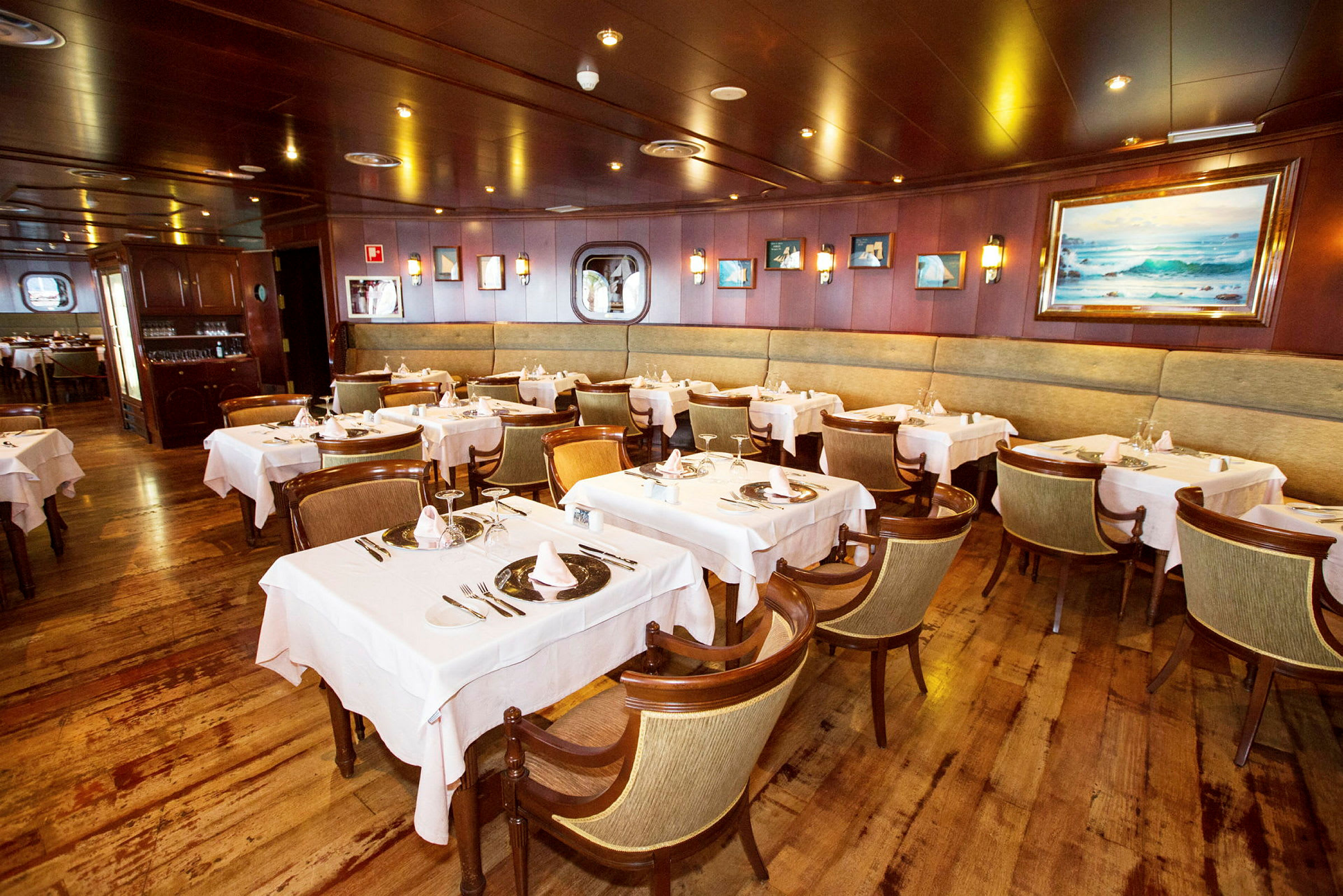 En restaurant med flere dækkede borde og stole, indrettet med træpaneler og vægdekorationer. (AI-genereret tekst)