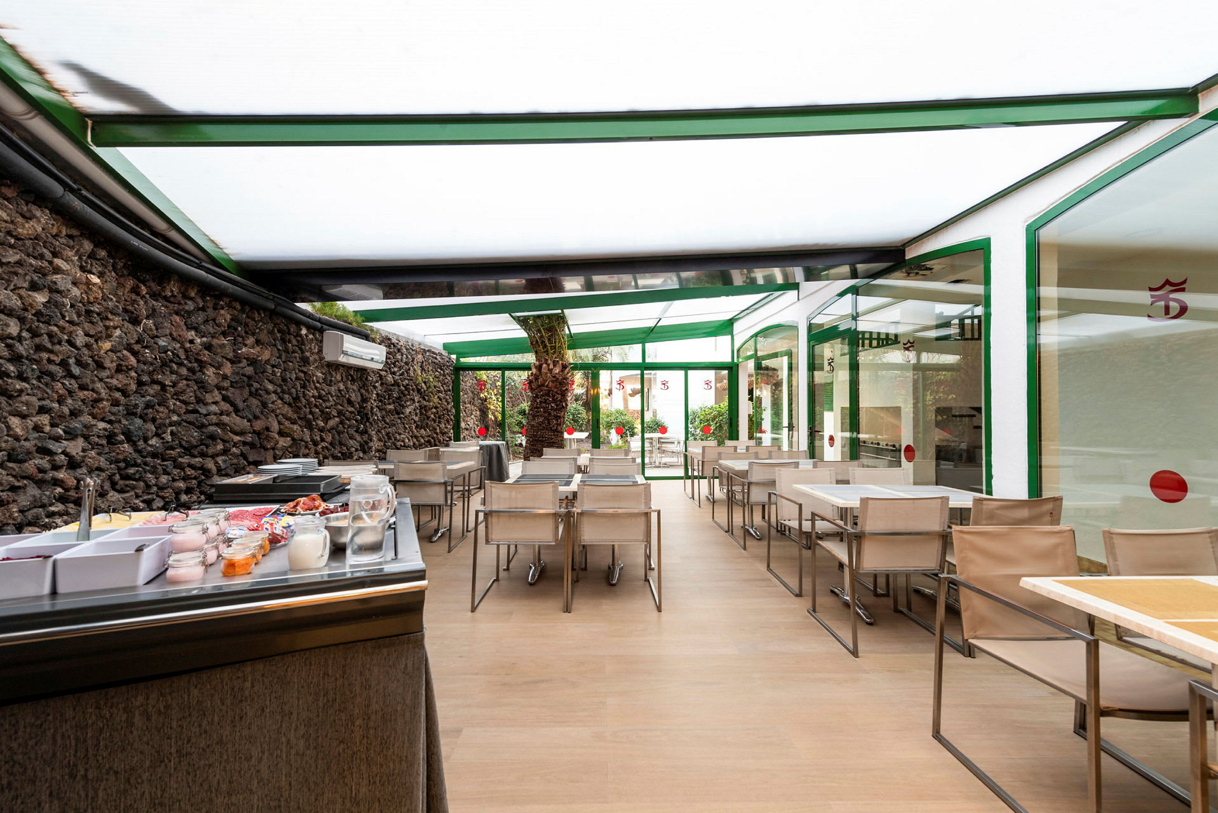 Spiseområde med borde og stole under tag samt en morgenmadsbuffet. (AI-genereret tekst)