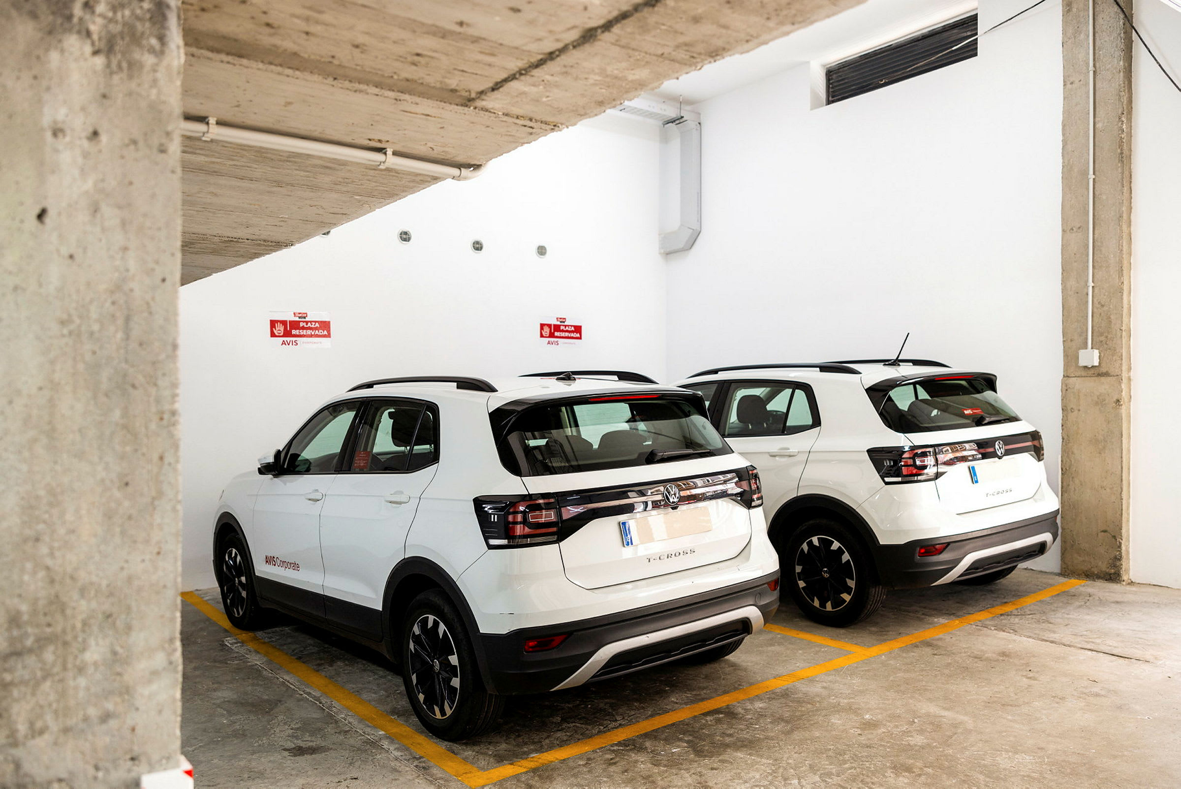 To hvide SUV-biler parkeret i en underjordisk parkeringsplads. (AI-genereret tekst)