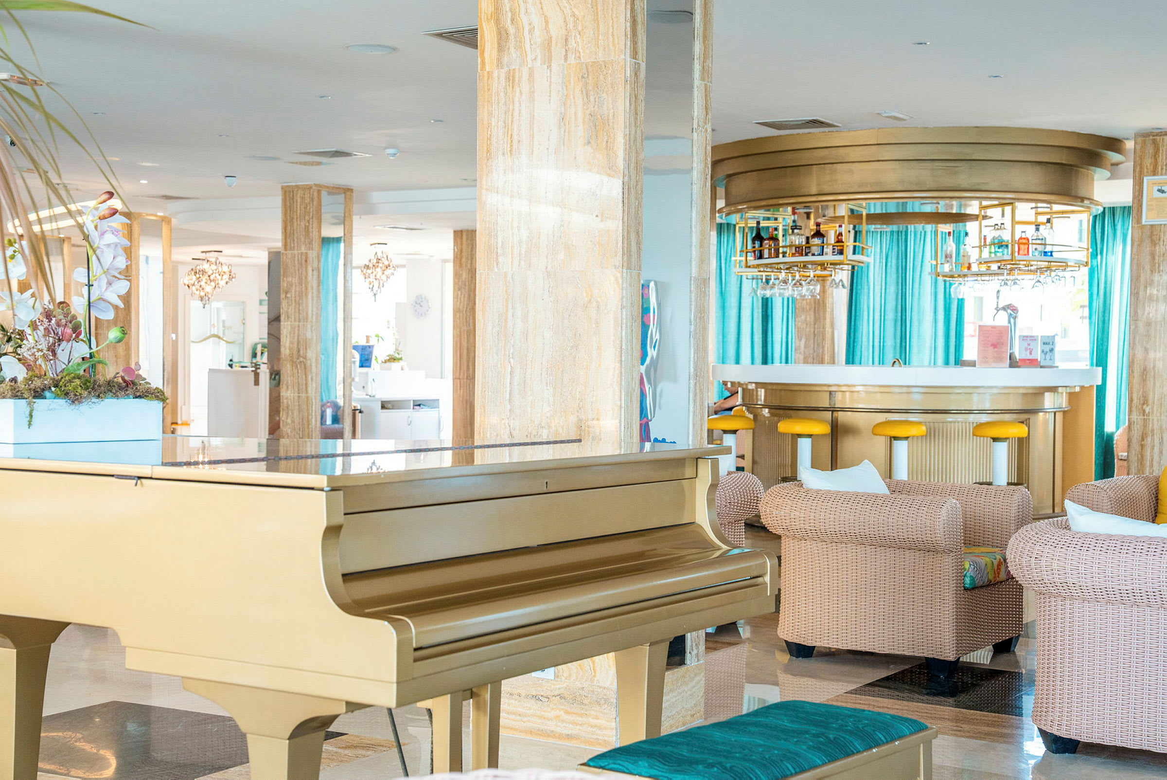 Et elegant hotelområde med et gyldent piano, komfortable siddegrupper og en moderne bar i baggrunden. (AI-genereret tekst)