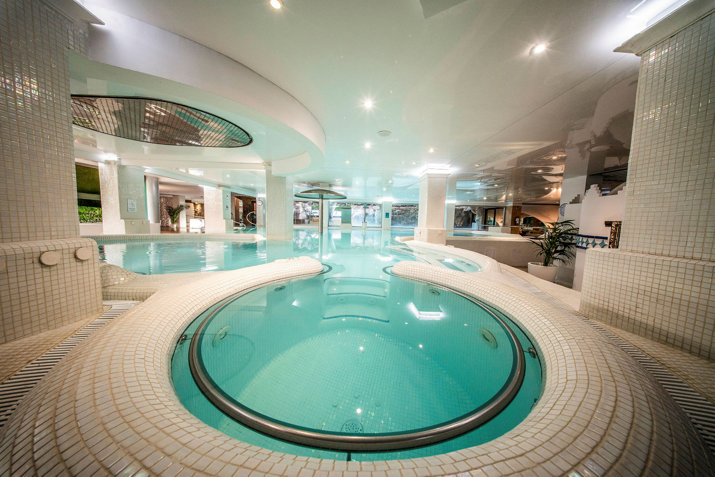 Et indendørs pool med moderne design omgivet af lyse fliser og belysning. (AI-genereret tekst)
