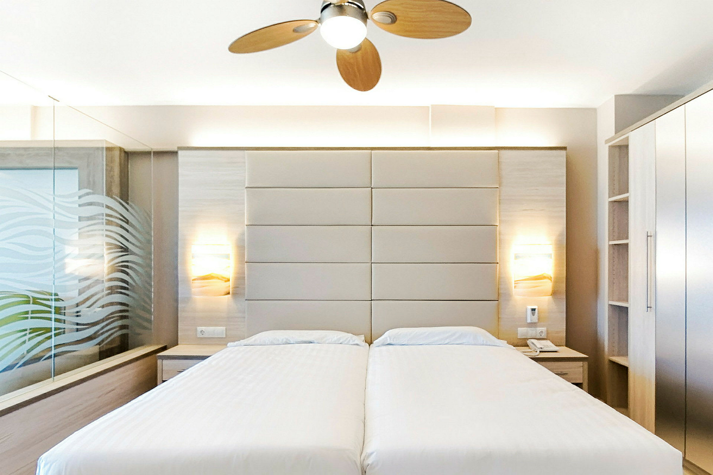 Hotelværelse med to enkeltsenge, moderne indretning og loftsventilator. (AI-genereret tekst)