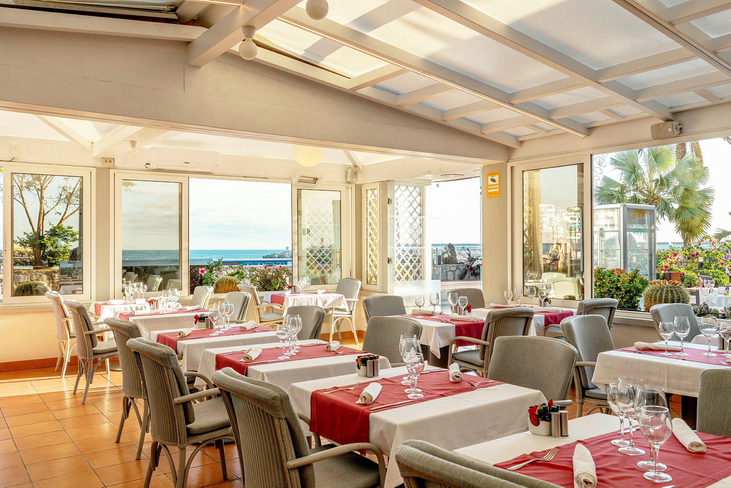 En restaurant med dækkede borde og glas med udsigt til havet. (AI-genereret tekst)