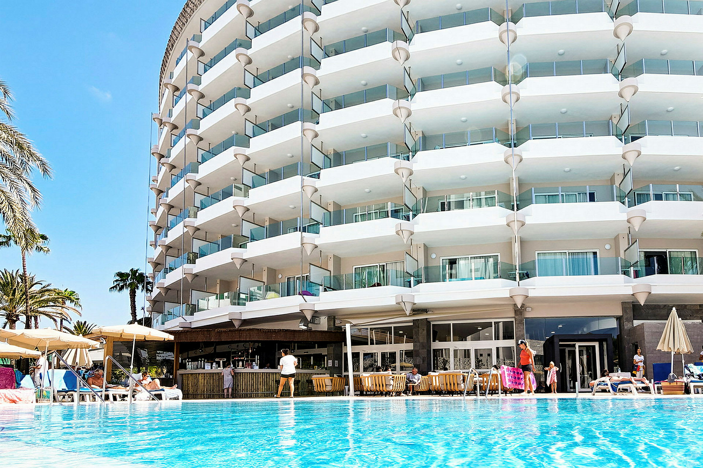 Et hotel med flere altaner ved en pool. (AI-genereret tekst)
