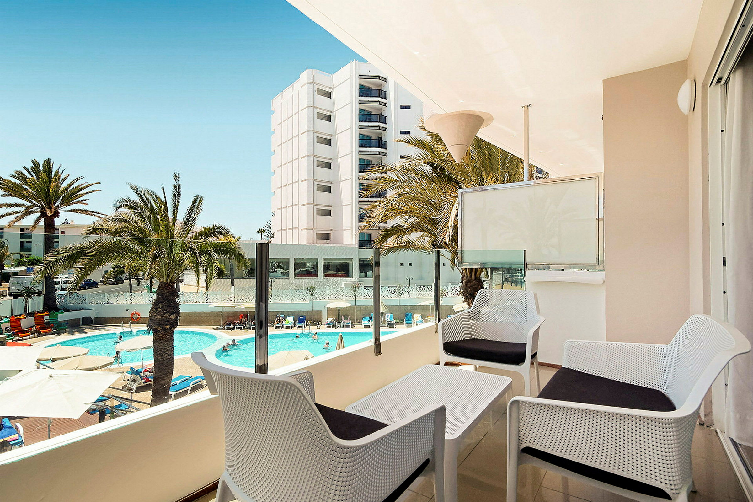 Udsigt fra en terrasse med siddeområde, swimmingpool og omkringliggende bygninger. (AI-genereret tekst)