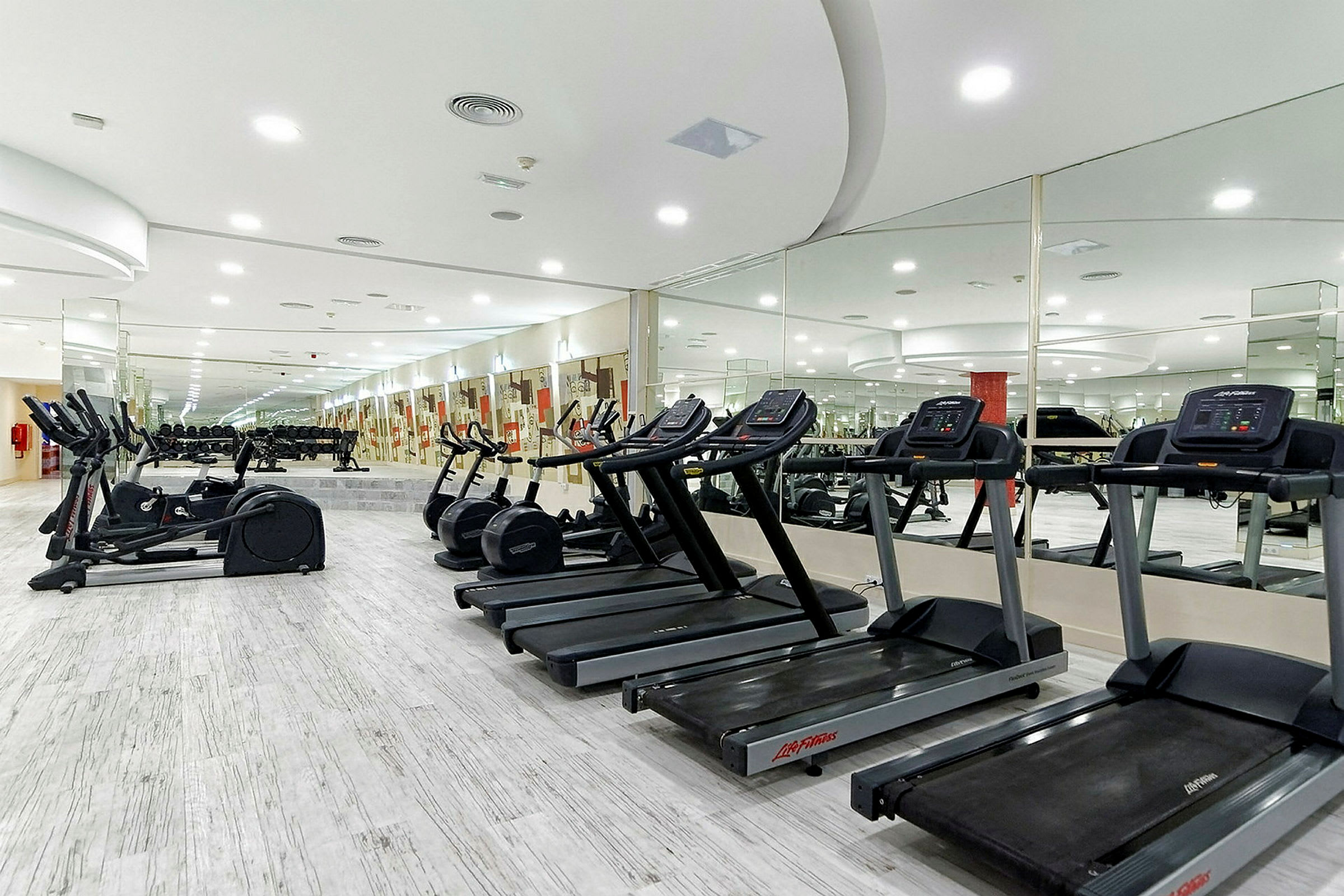 Et fitnesscenter med træningsmaskiner, spejlvægge og moderne belysning. (AI-genereret tekst)