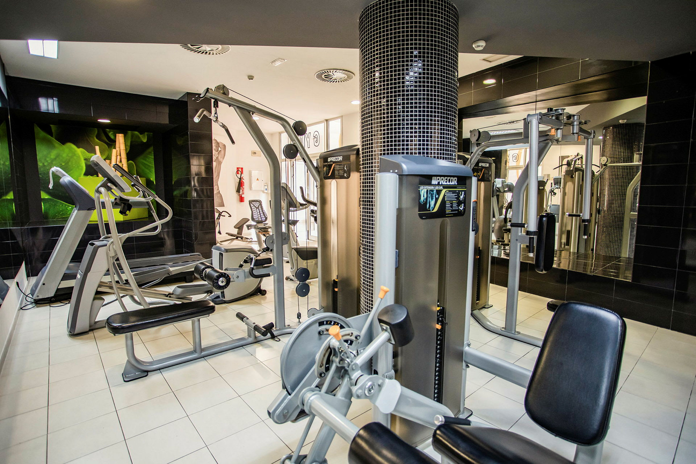 Et fitnesscenter med forskellige træningsmaskiner til styrke og kondition. (AI-genereret tekst)
