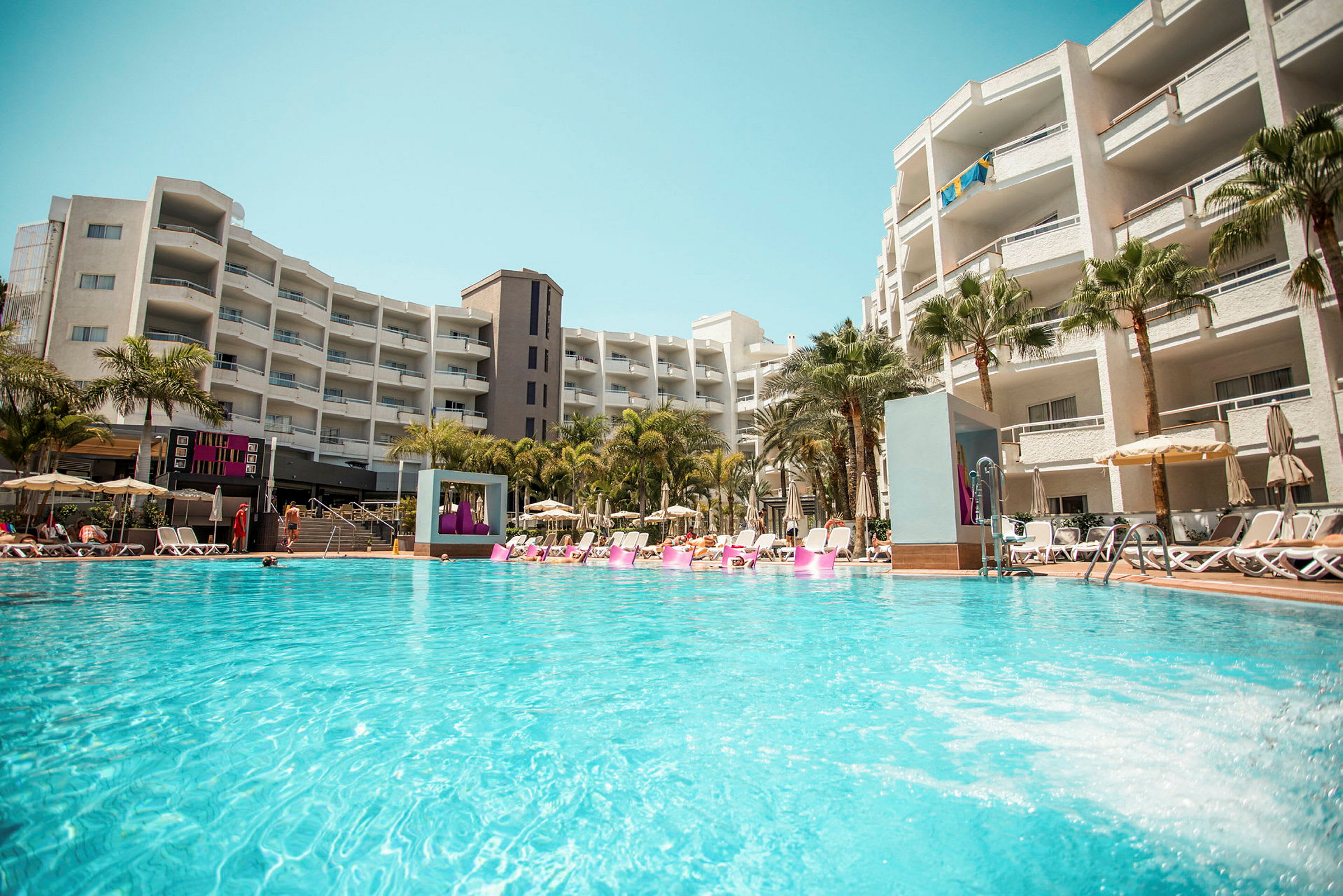 En hotelpool ved et større bygningskompleks. (AI-genereret tekst)