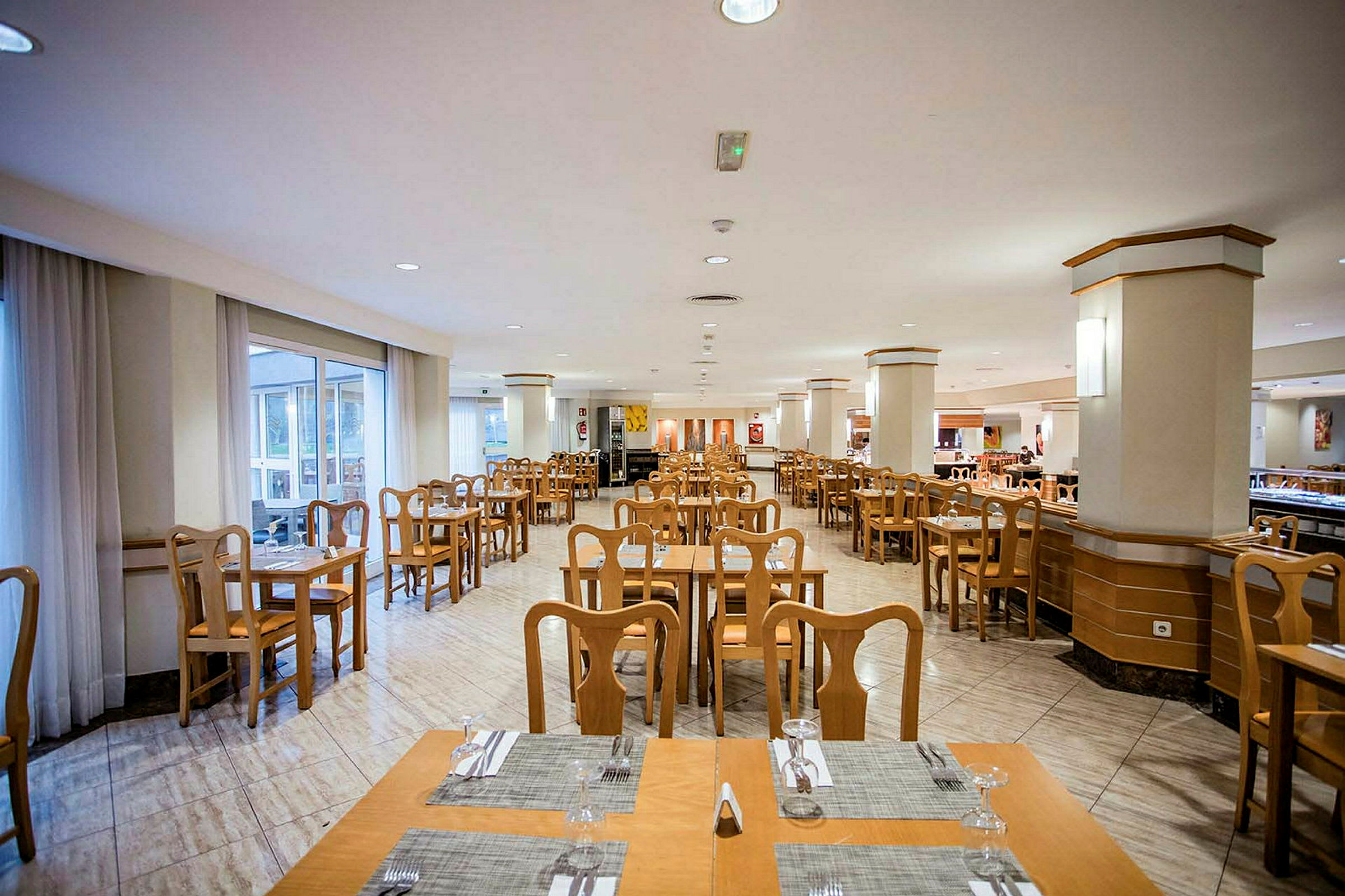 Restaurant med borde og stole i træ samt duge og glas. (AI-genereret tekst)
