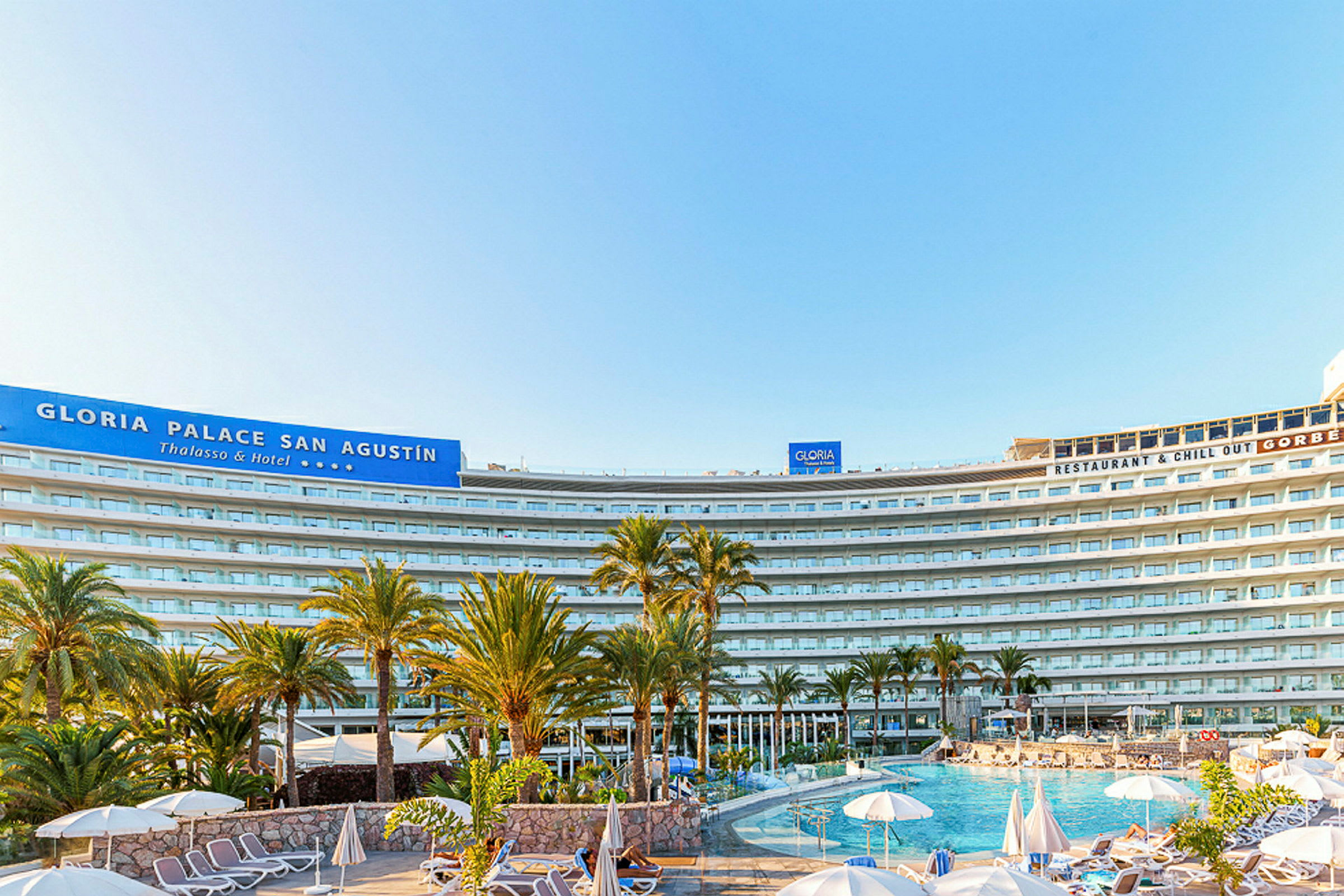 Billede af hotellet Gloria Palace San Agustín med pool og liggestole i forgrunden. (AI-genereret tekst)