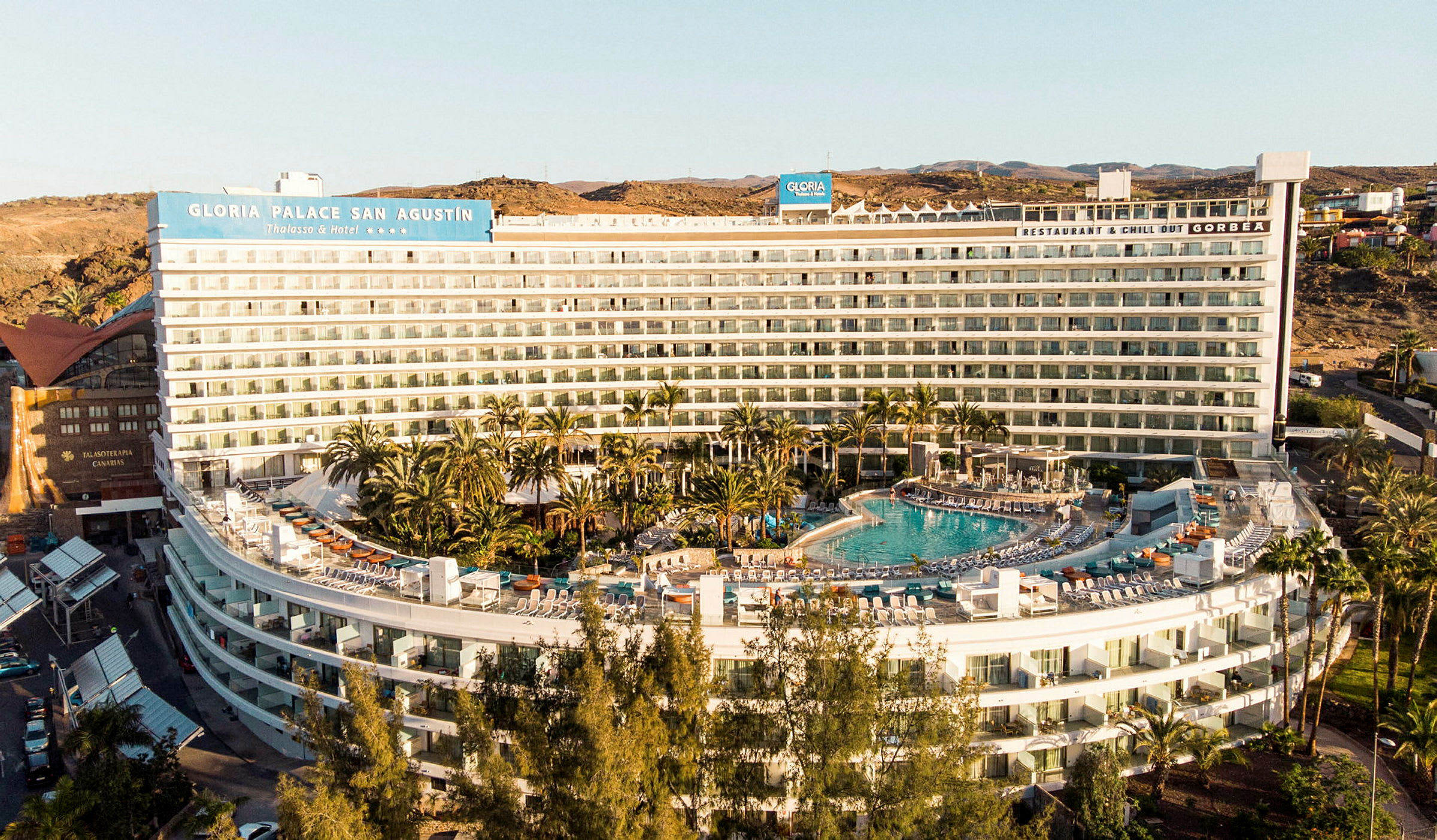 Hotelbygning med pool og omgivelser af grønne områder. (AI-genereret tekst)