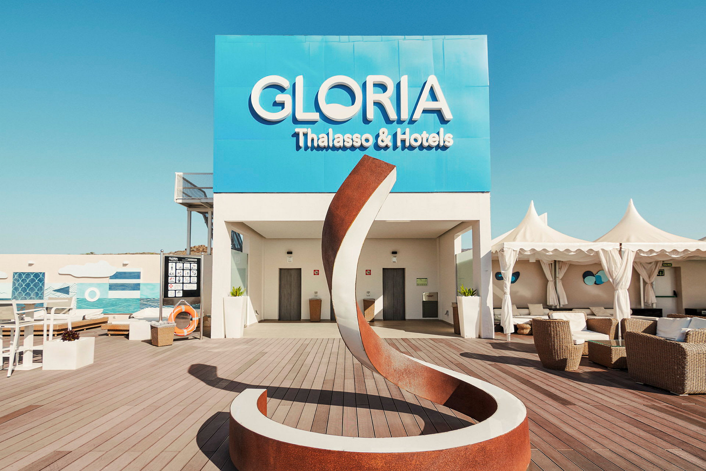 Udendørsområde ved Gloria Thalasso & Hotels med moderne skulptur og siddepladser. (AI-genereret tekst)