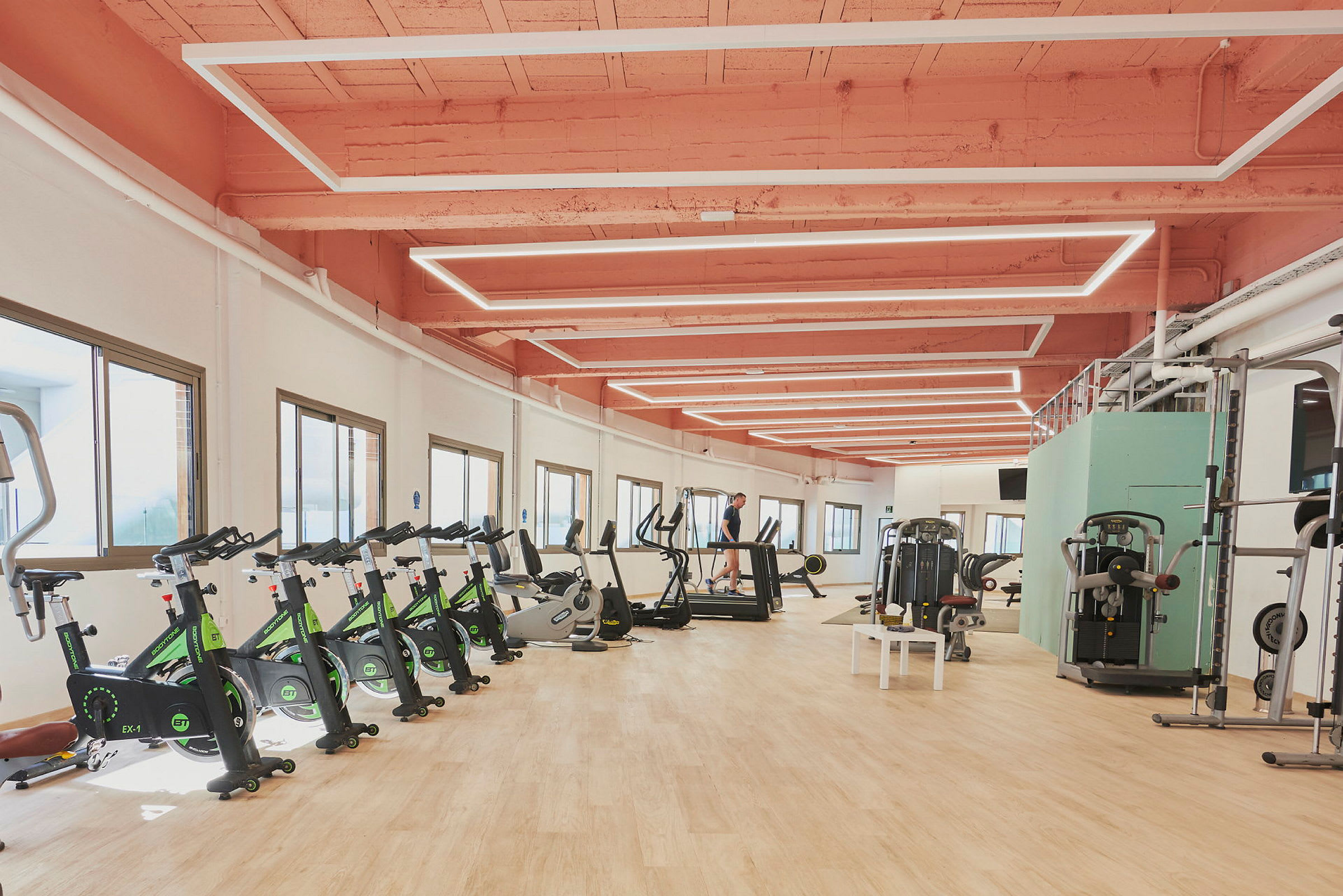 Et fitnesscenter med træningsudstyr, herunder motionscykler, løbebånd og styrketræningsmaskiner. (AI-genereret tekst)
