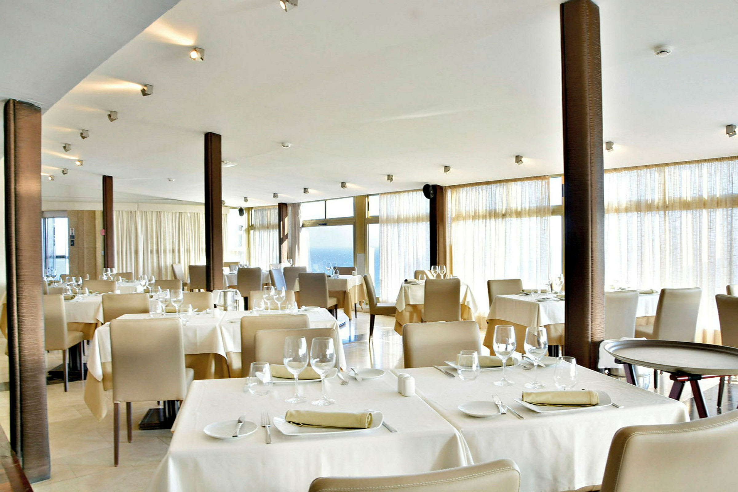Billede af en restaurant med dækkede borde og stole. (AI-genereret tekst)