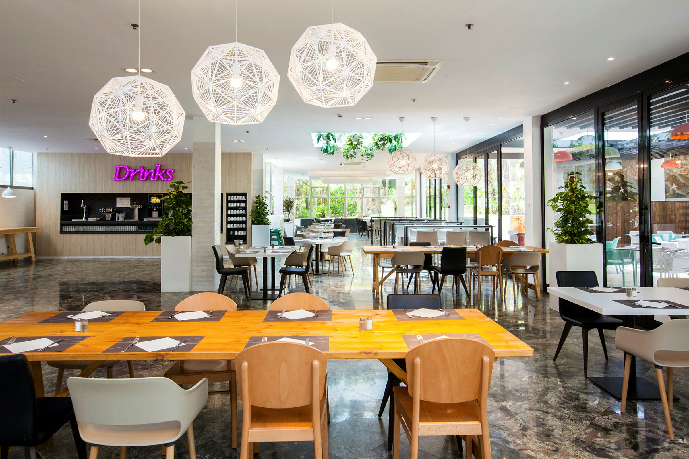 En lys og moderne restaurant med træborde og stole samt dekorative hængende lamper. (AI-genereret tekst)