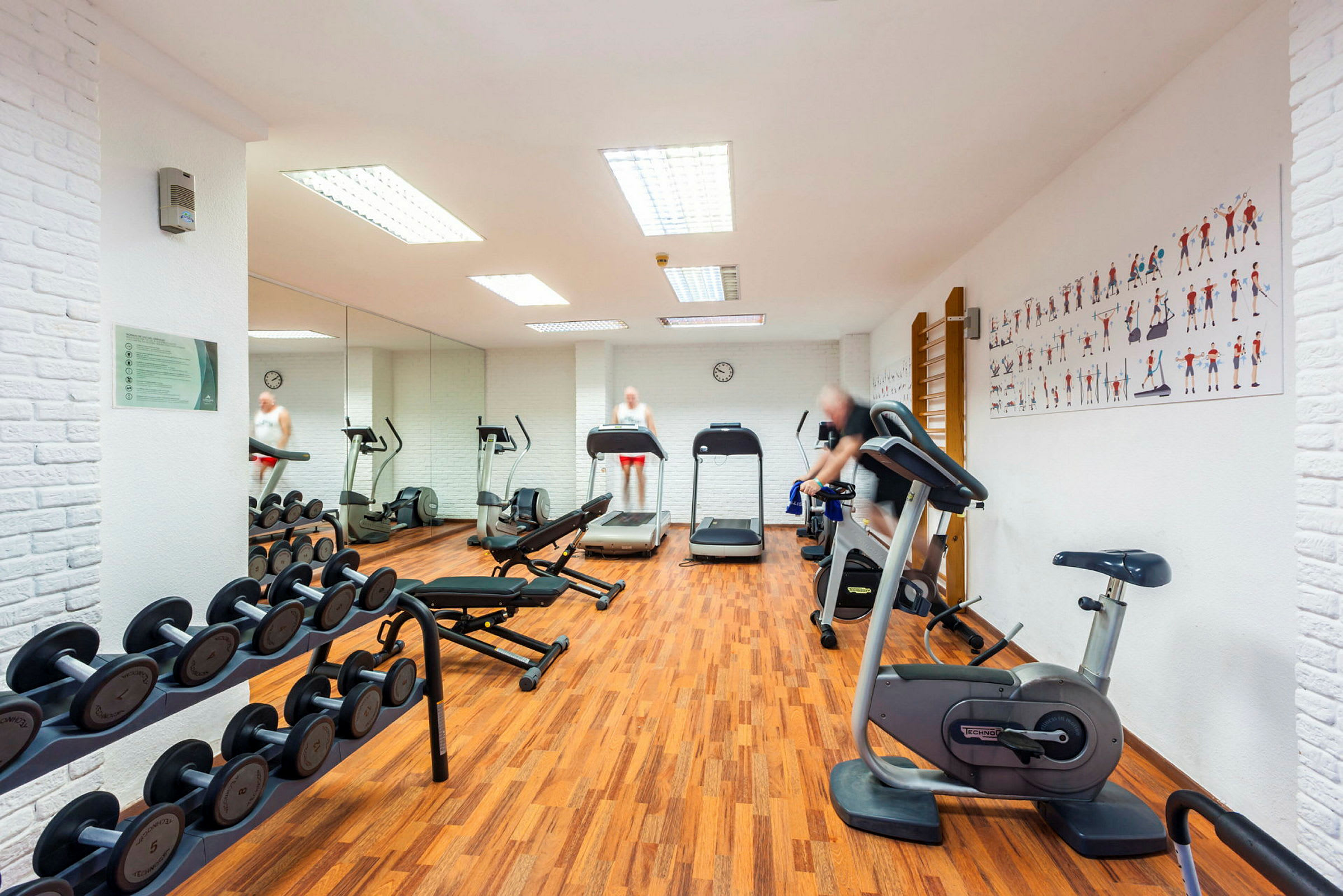 Billede af et fitnesscenter med træningsudstyr såsom løbebånd, cykler og håndvægte. (AI-genereret tekst)