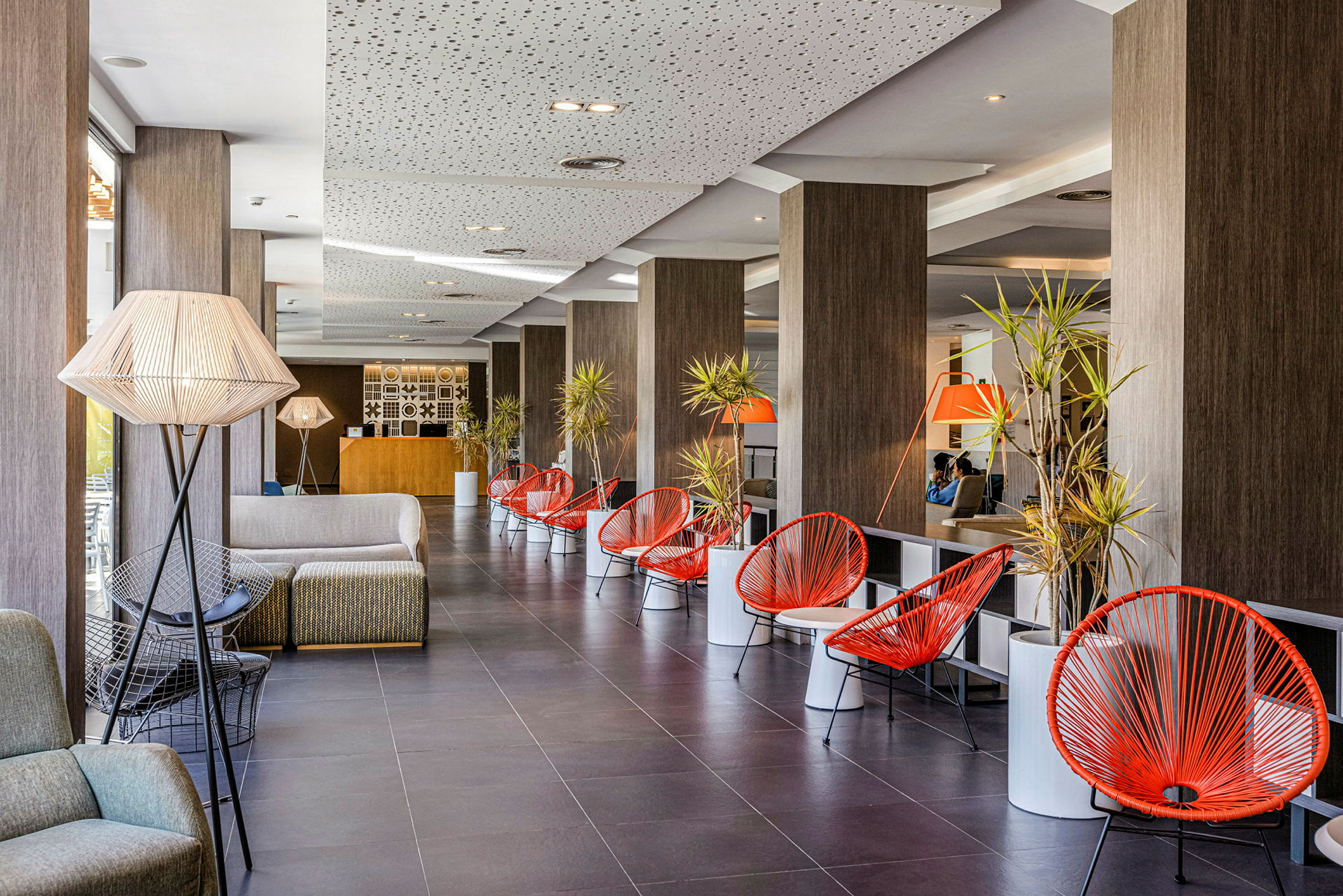 Hotellets foyer med siddeområder og røde stole. (AI-genereret tekst)