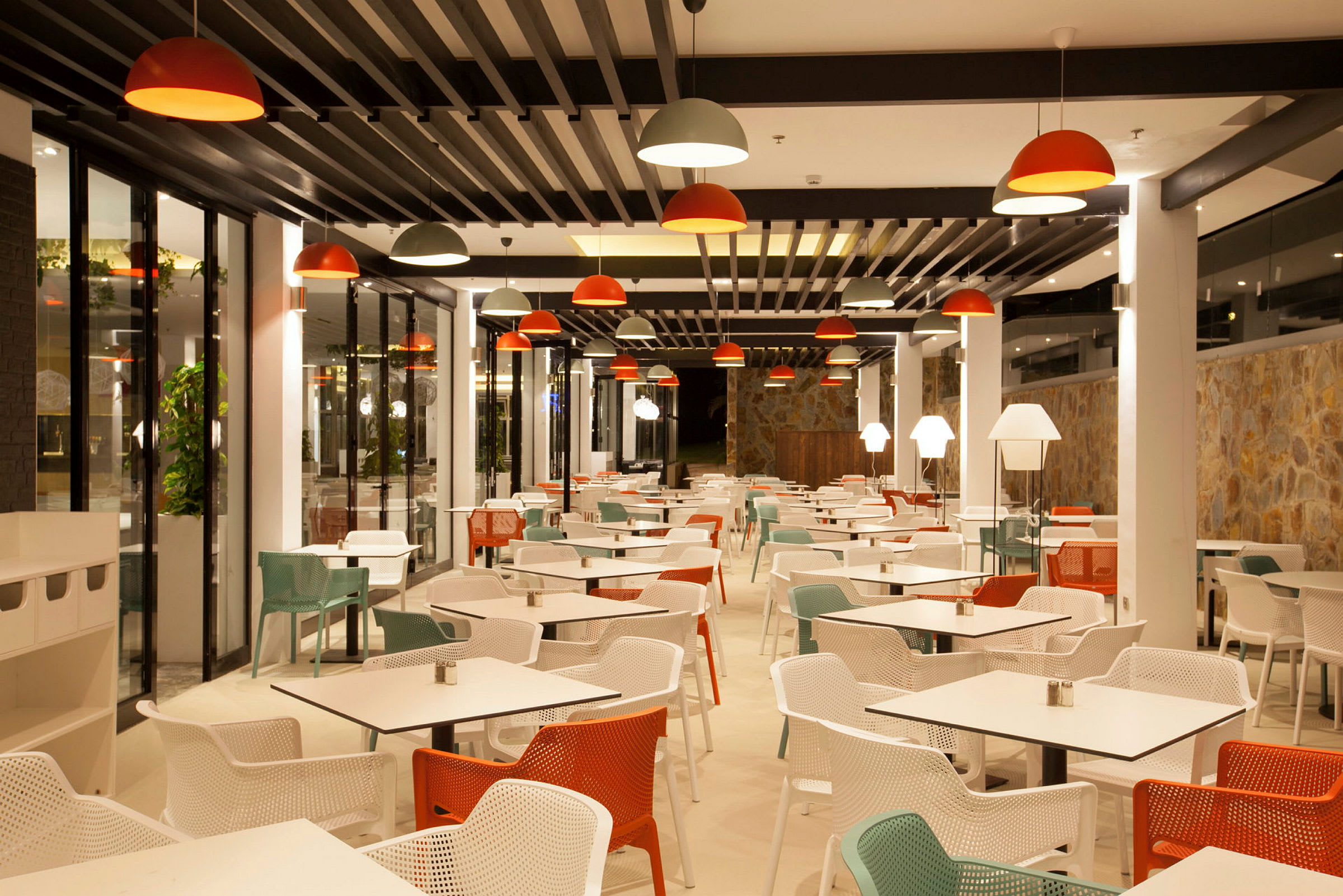 Interiør af en moderne restaurant med siddepladser. Belysning med rødt og hvidt. (AI-genereret tekst)