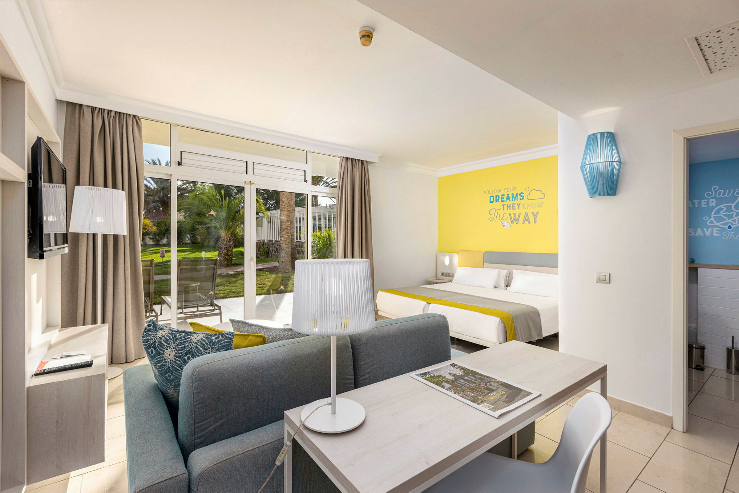Moderne hotelværelse med siddeområde, seng og udsigt til have. (AI-genereret tekst)