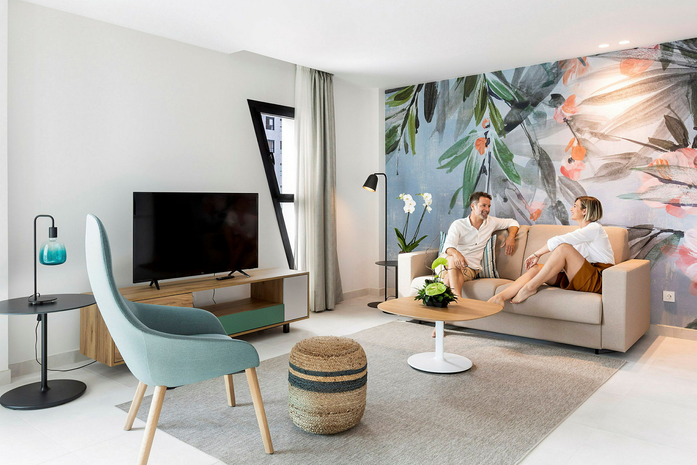 Et moderne opholdsområde med sofa, bord og vægdekoration med botanisk tema. (AI-genereret tekst)