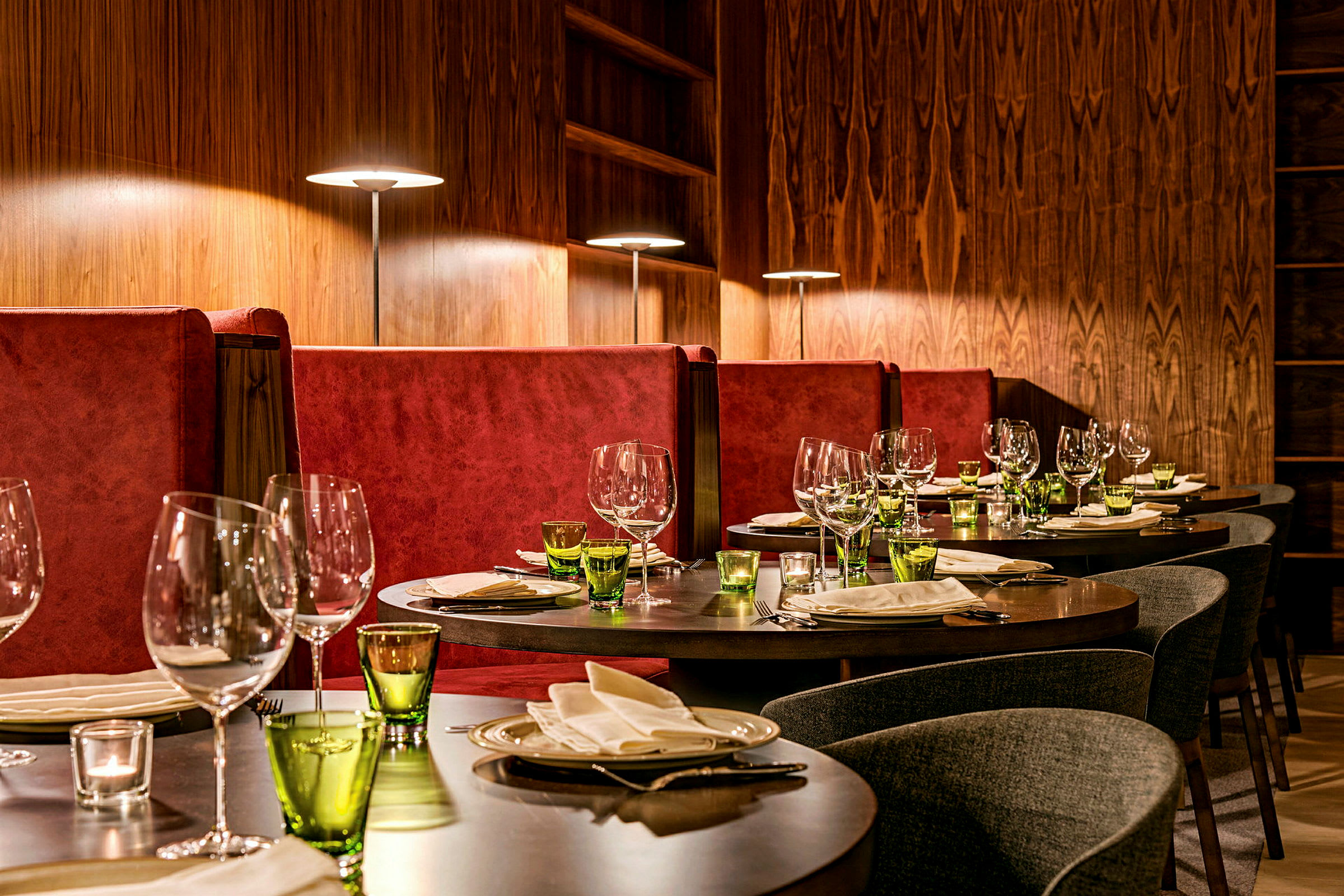Elegant restaurant med opdækkede borde og røde sofaer. (AI-genereret tekst)