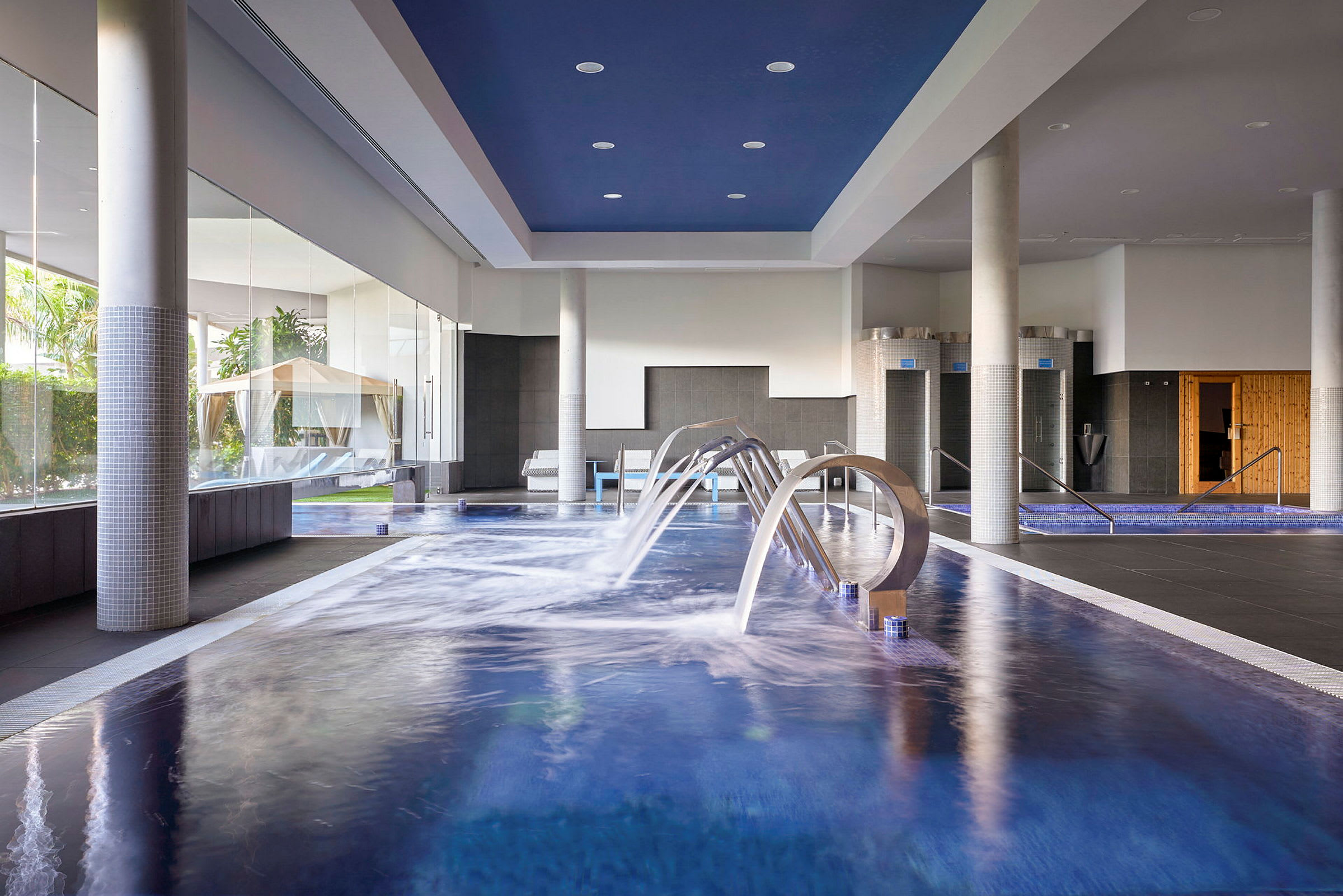 Indendørs pool med vandfunktioner og omkringliggende spa-område. (AI-genereret tekst)