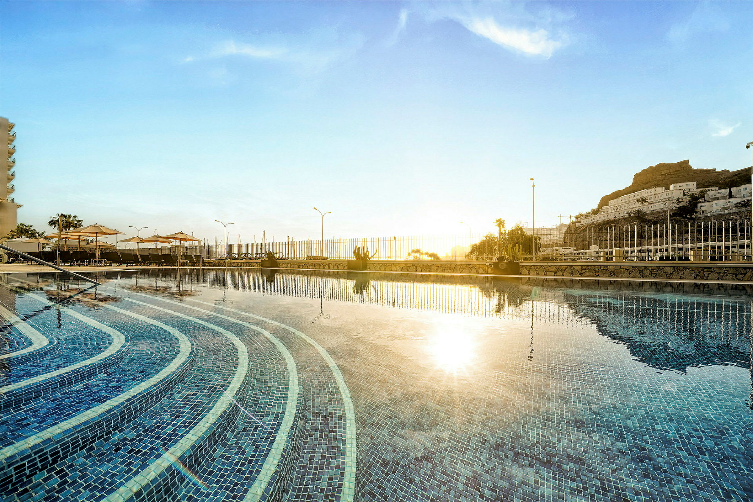 En solnedgang over en pool med trin og omgivende hegn. (AI-genereret tekst)