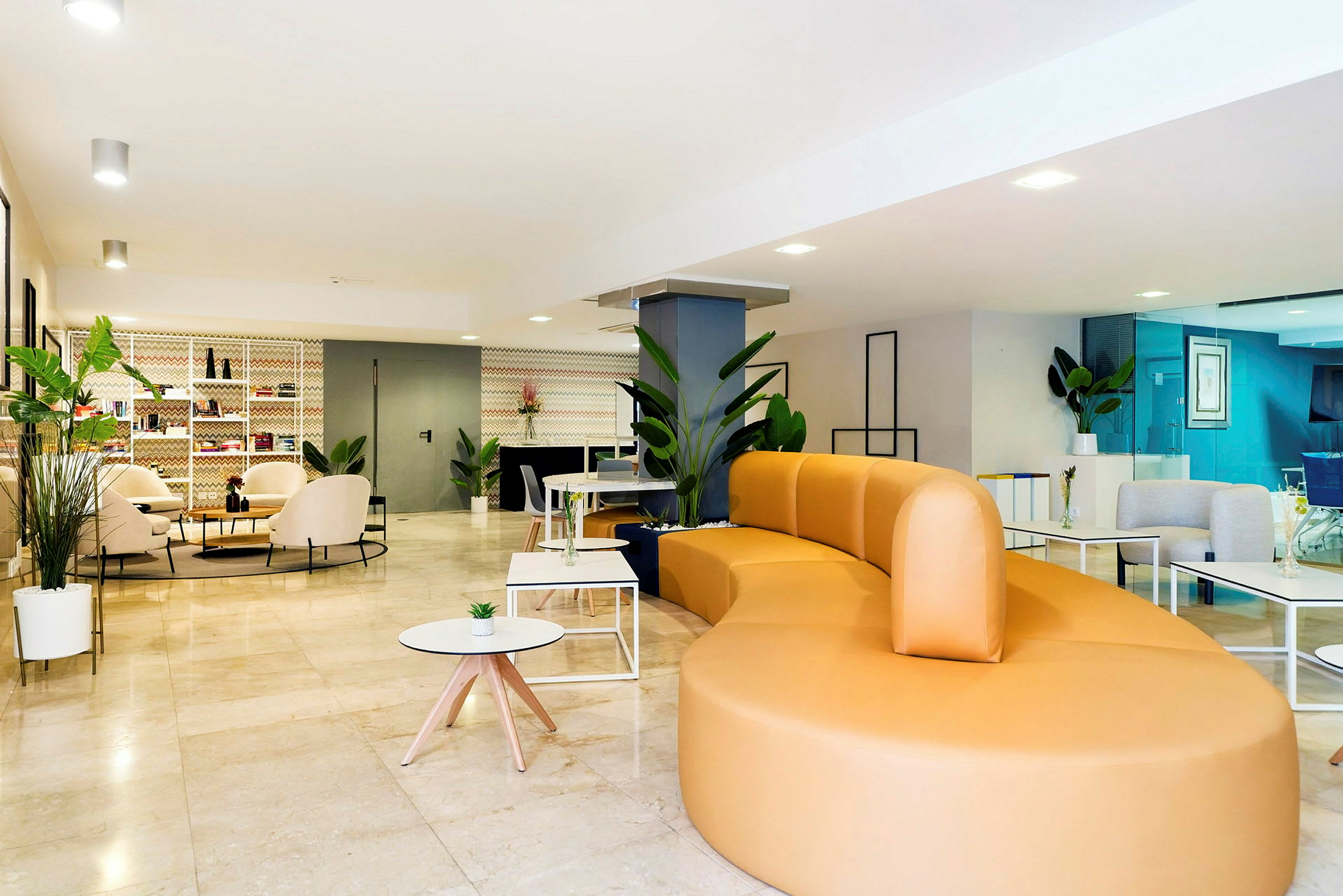 En lys og moderne lounge med en stor gul sofa, borde og grønne planter. (AI-genereret tekst)