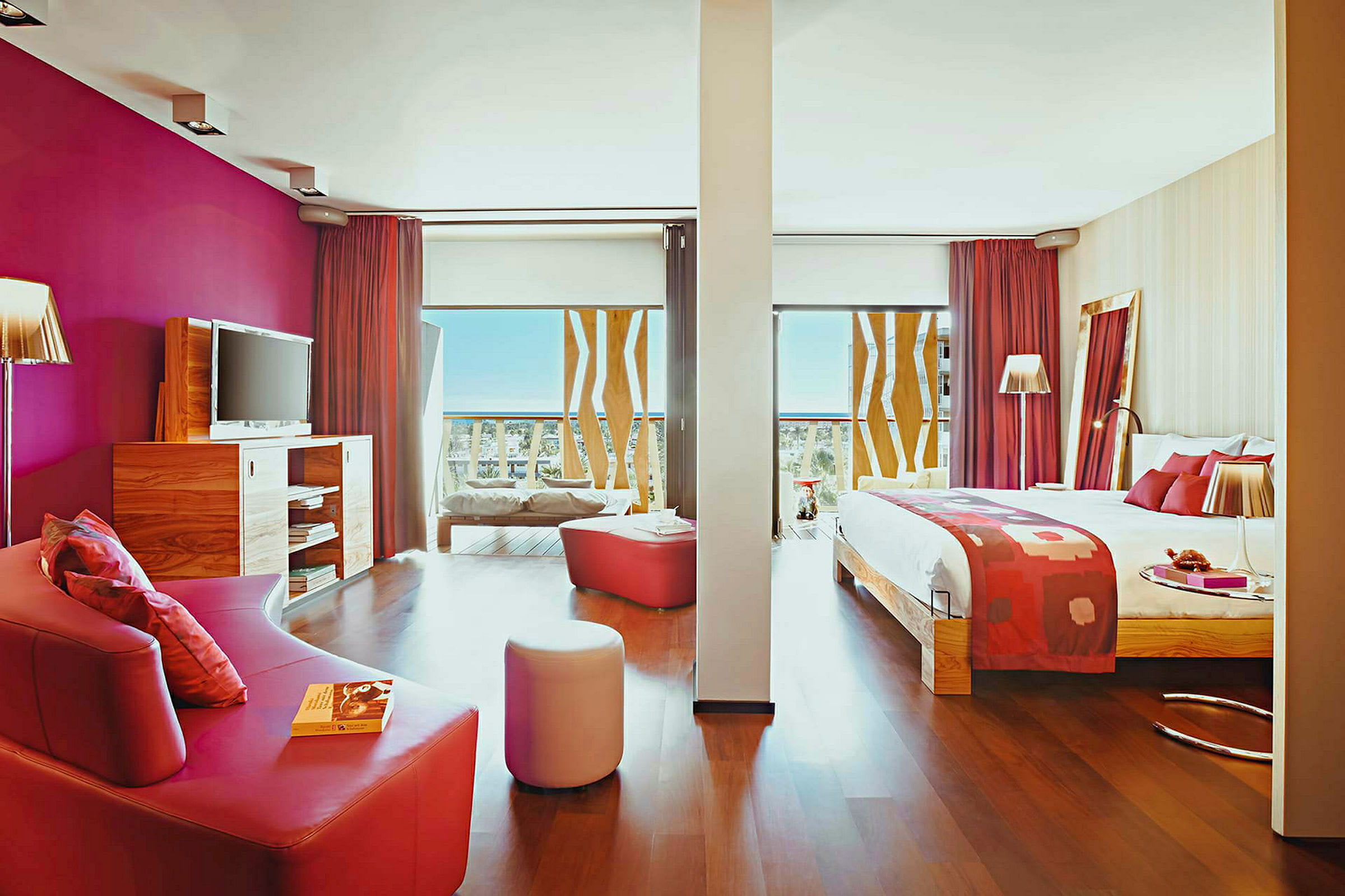 Hotelværelse med seng, sofa og moderne indretning med pink detaljer. (AI-genereret tekst)