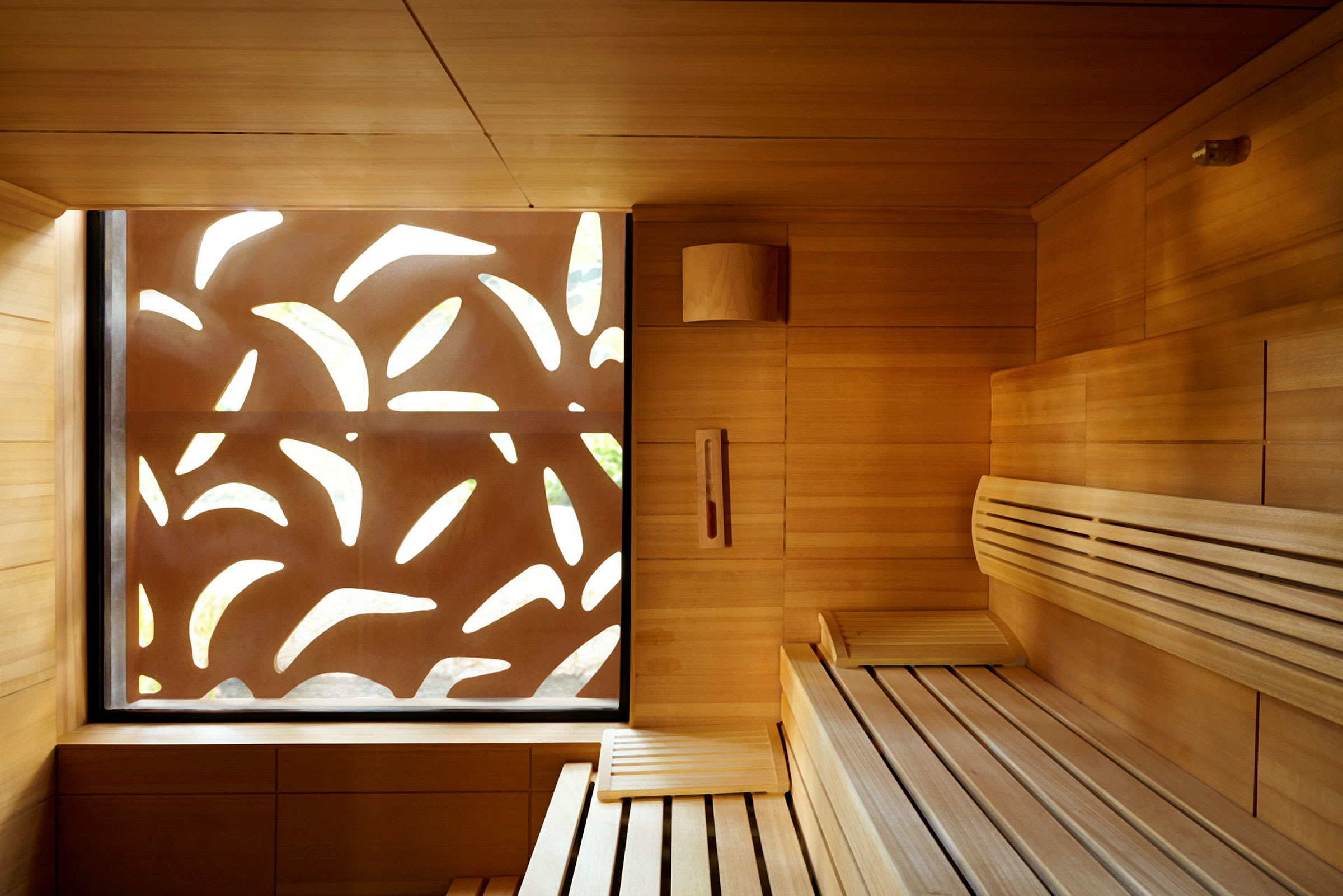 Interiør af en moderne sauna med træpaneler og et dekorativt mønster på et vindue. (AI-genereret tekst)