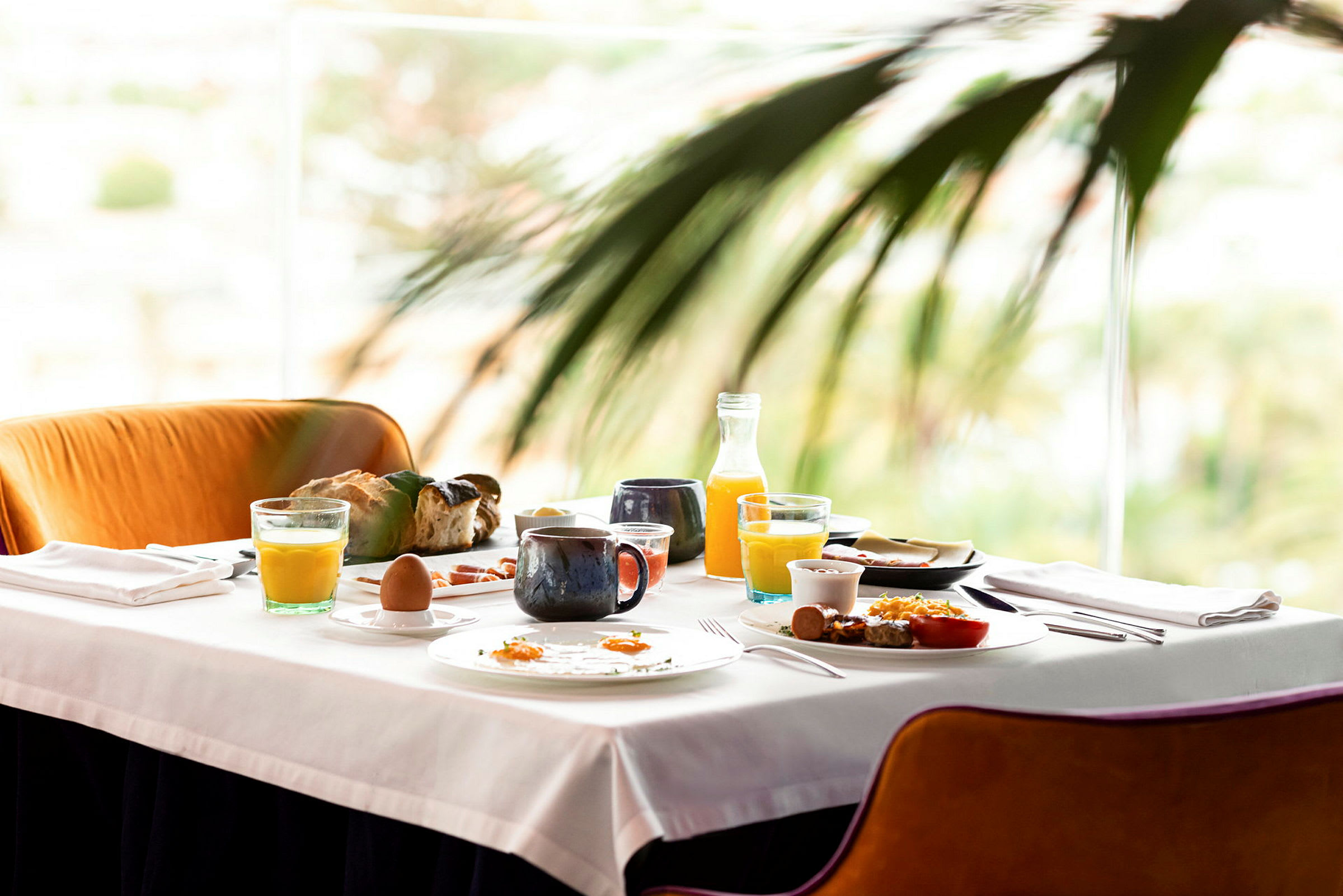 Et bord dækket med morgenmad, inklusive juice, kaffe, brød og æg. (AI-genereret tekst)