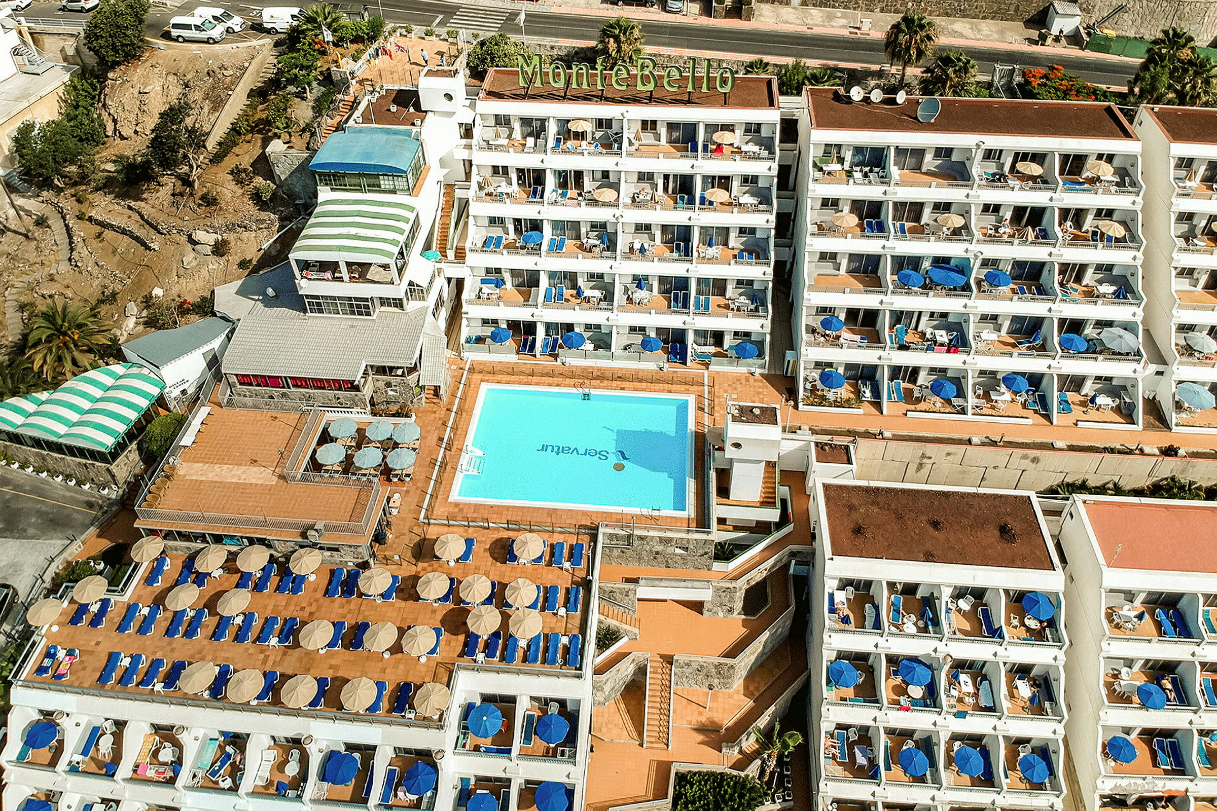 Luftfoto af hotel Montebello med pool og liggestole. (AI-genereret tekst)
