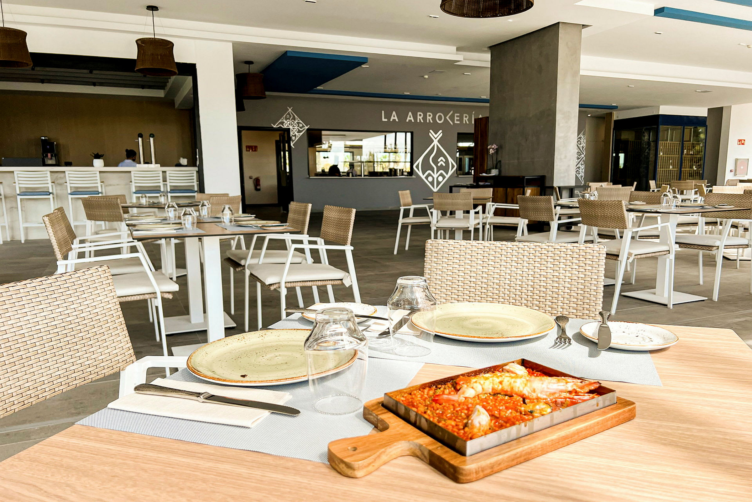 Billede af en restaurant med dækkede borde og serveret ret, en paella. (AI-genereret tekst)