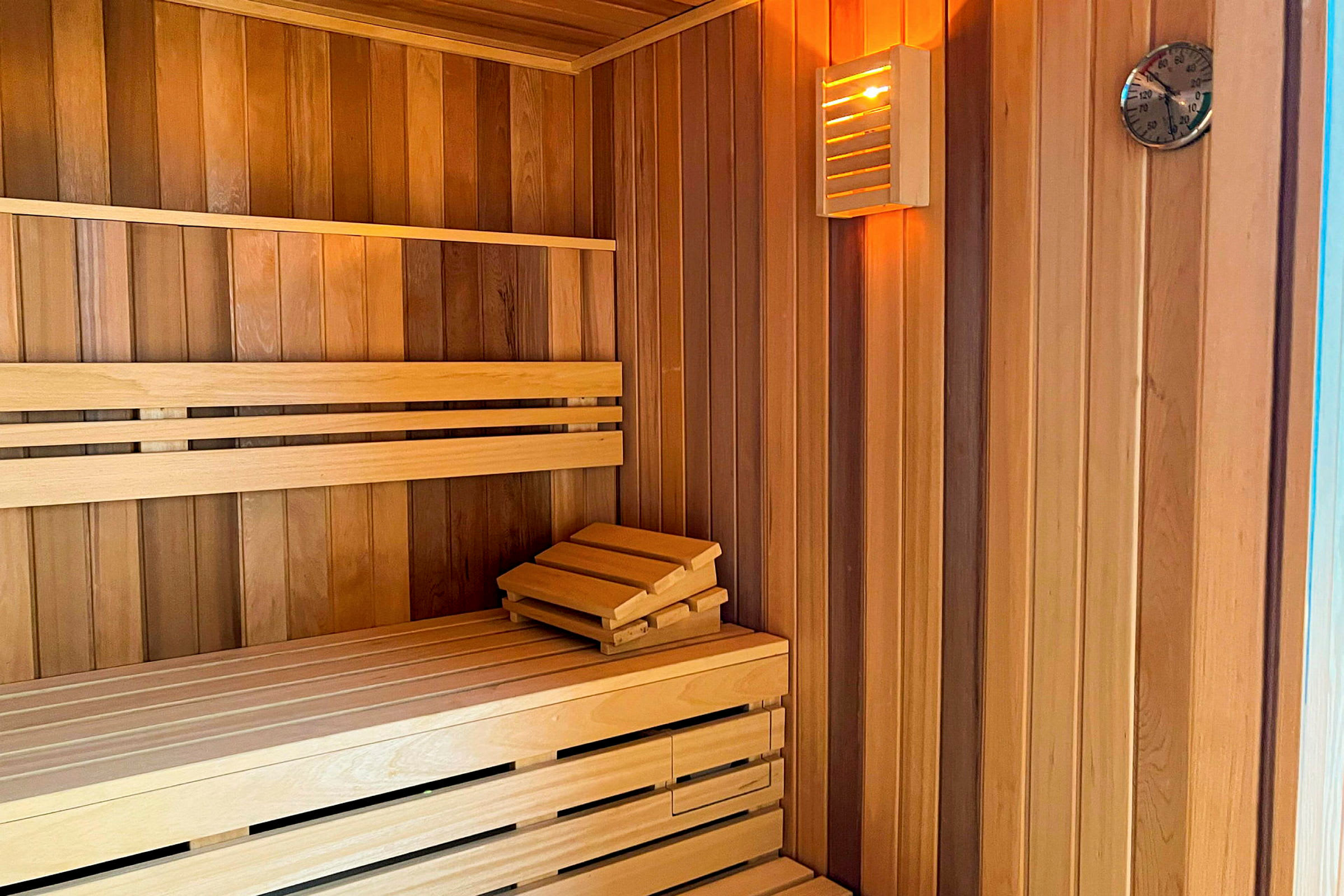 En sauna med træinteriør, bænk og termometer. (AI-genereret tekst)