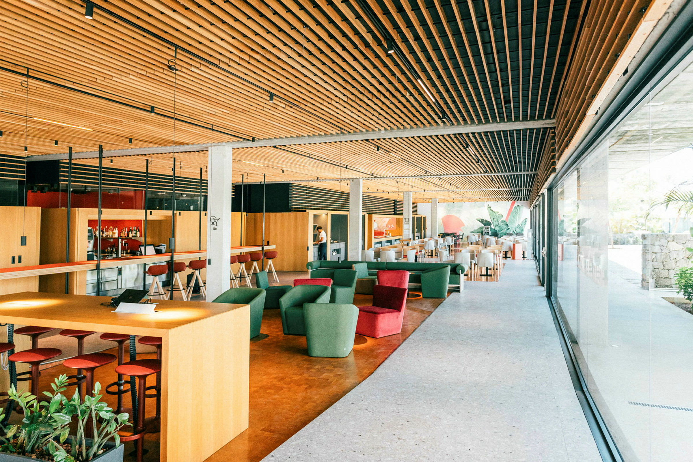 Interiør af en moderne lounge med siddepladser, barområde og store vinduer. (AI-genereret tekst)
