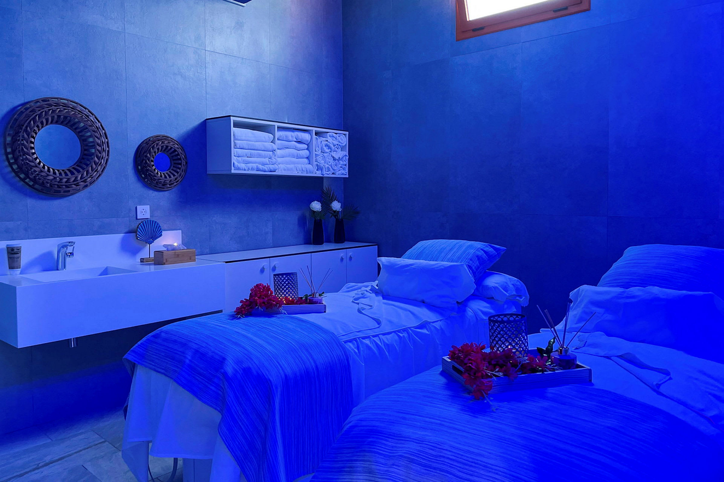 Et spa-rum med to massageborde, blå belysning og dekorative detaljer. (AI-genereret tekst)