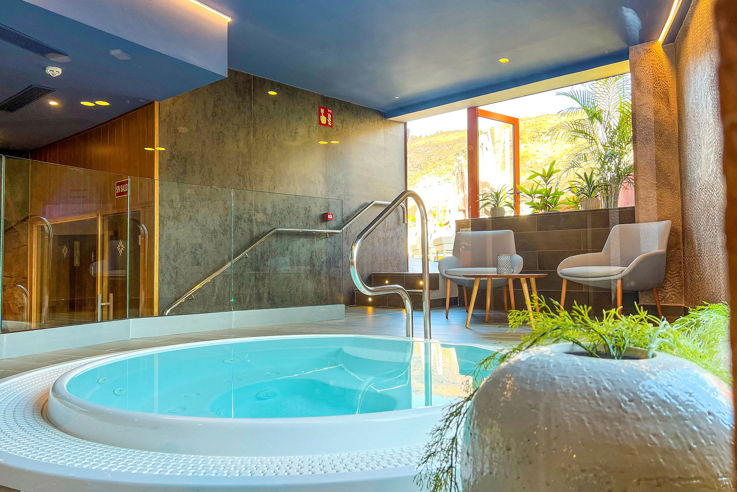 Indendørs spa med en boblebad, siddepladser og planter. (AI-genereret tekst)