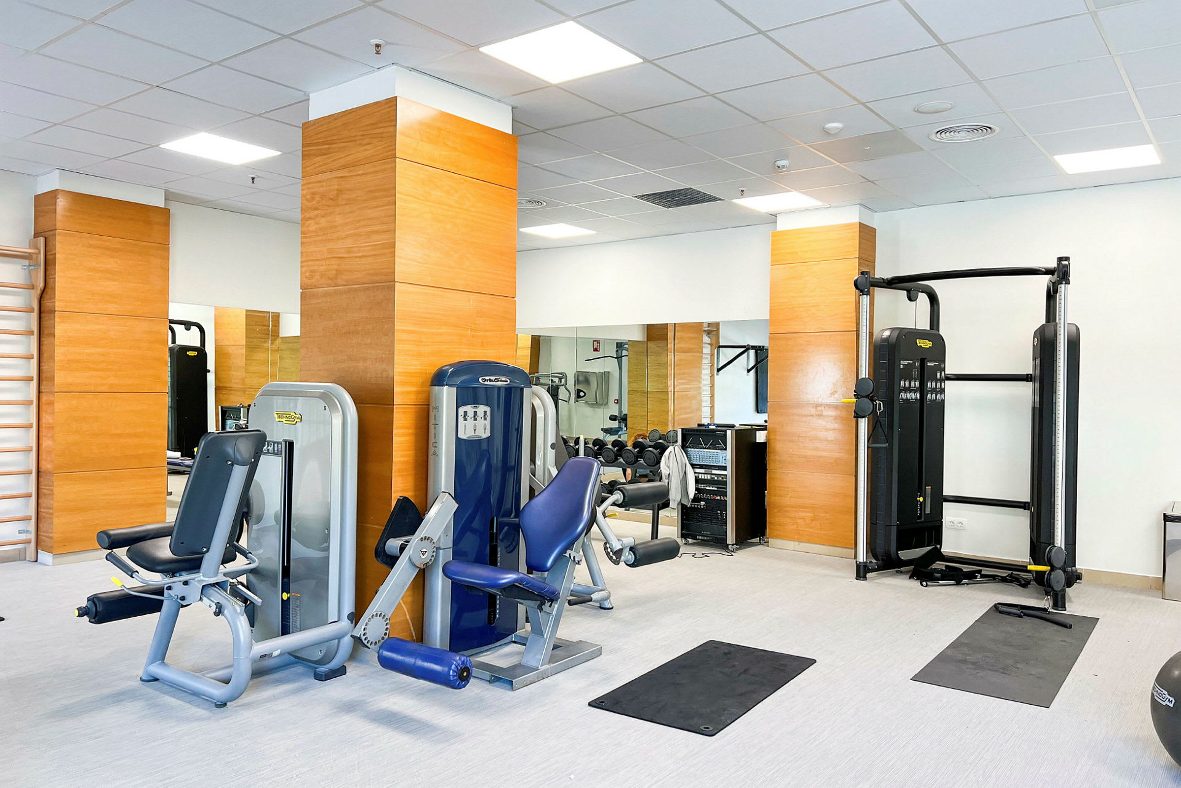 Billede af et fitnesscenter med træningsudstyr og spejle. (AI-genereret tekst)