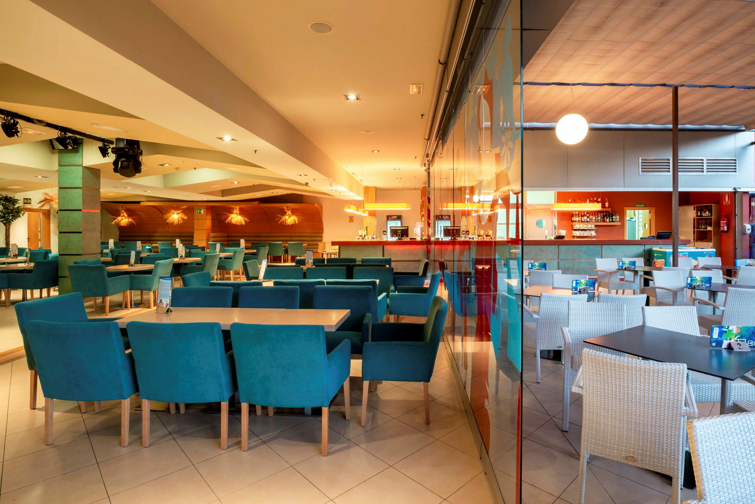 Interiør af en restaurant med borde og stole, samt en bardisk i baggrunden. (AI-genereret tekst)