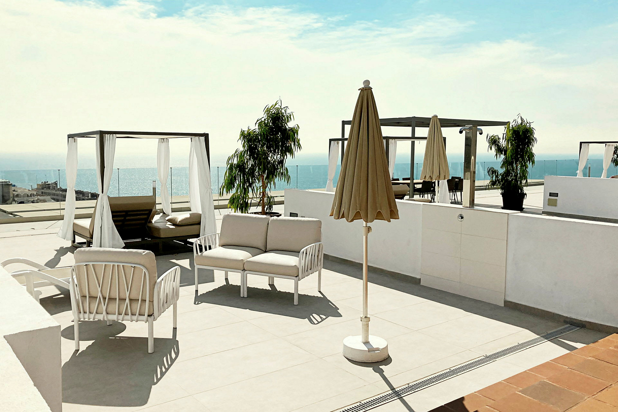 En terrasse med liggestole, parasol og udsigt over havet. (AI-genereret tekst)