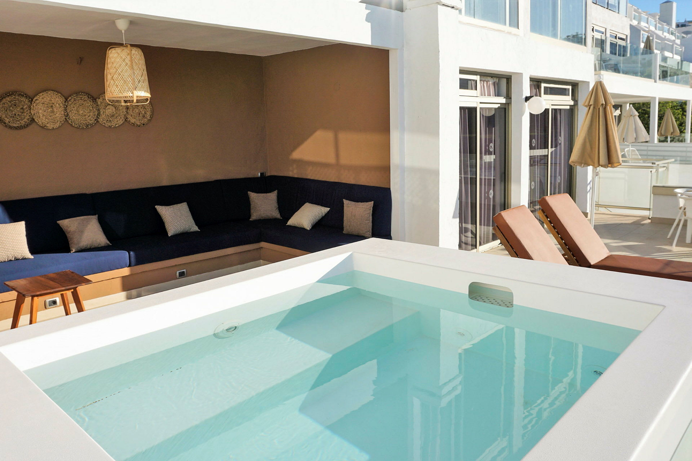 Udendørs område med pool, liggestole og en siddegruppe med sofaer. (AI-genereret tekst)