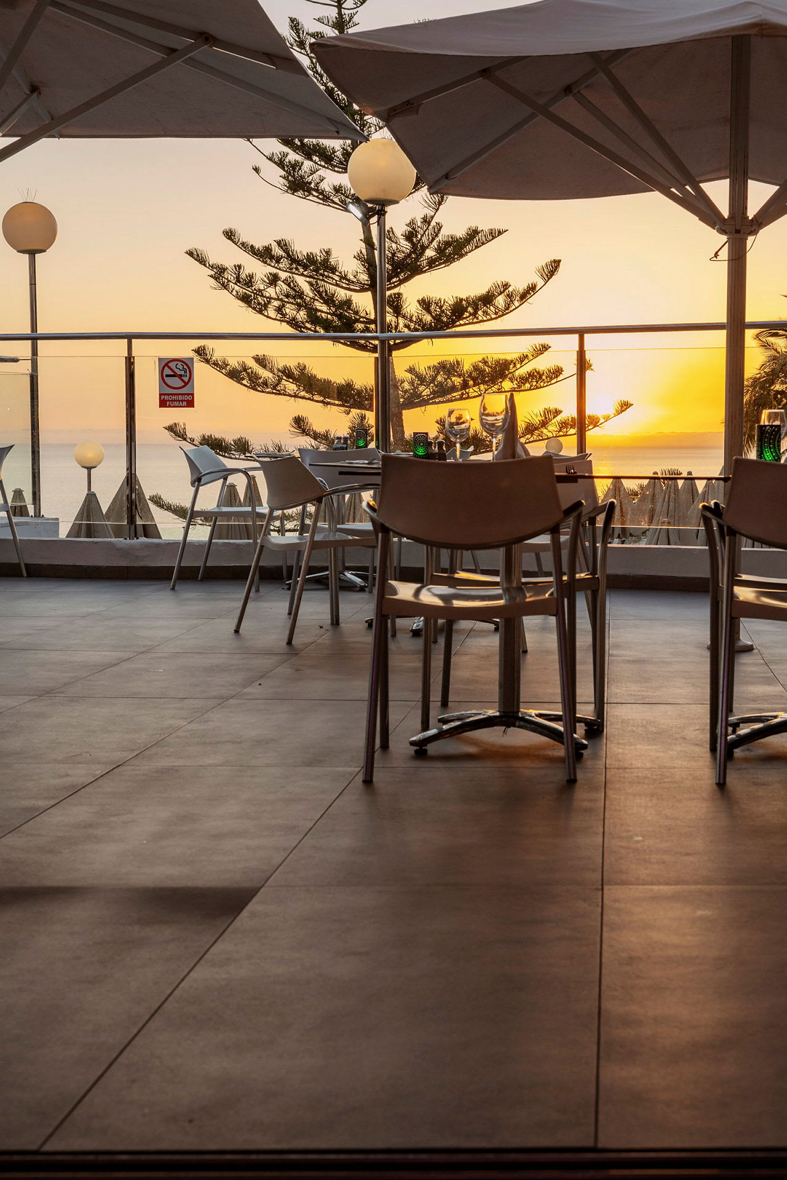 Restaurant med udendørs servering og havudsigt ved solnedgang. (AI-genereret tekst)