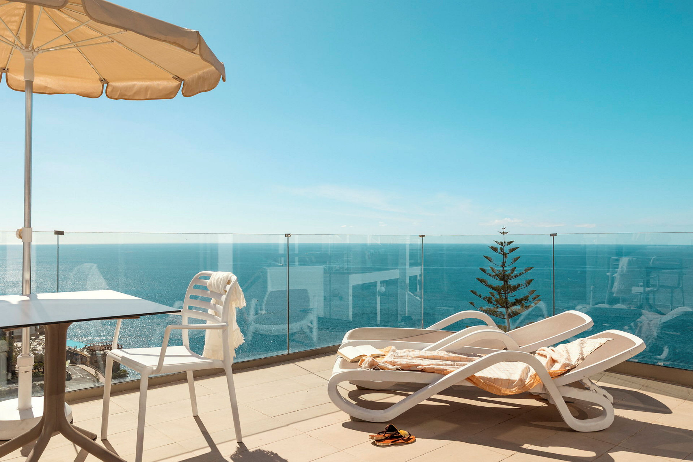 Terrasse med liggestole, parasol og havudsigt. (AI-genereret tekst)