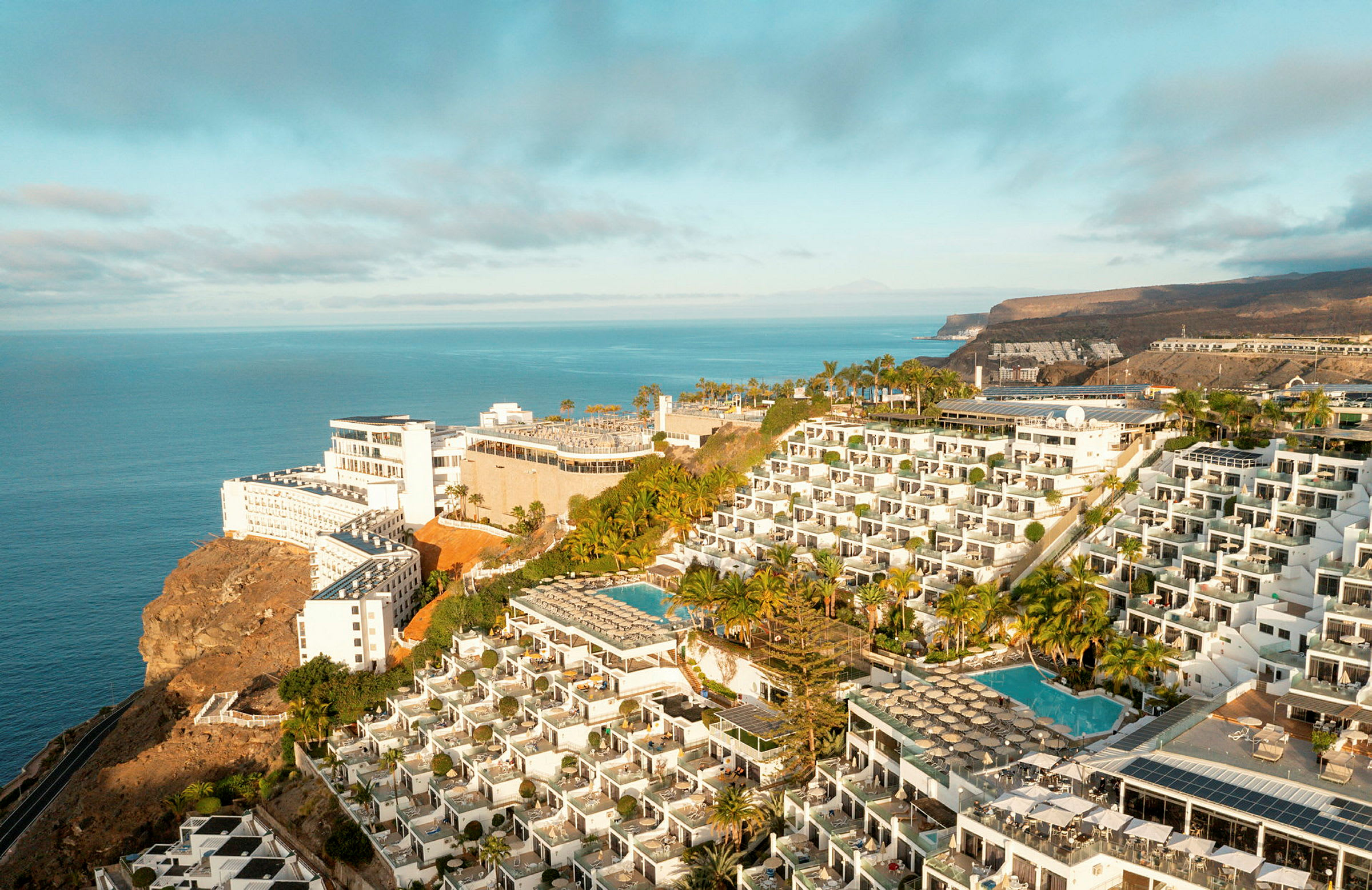Hotelkompleks på en klippe med swimmingpools og havudsigt. (AI-genereret tekst)