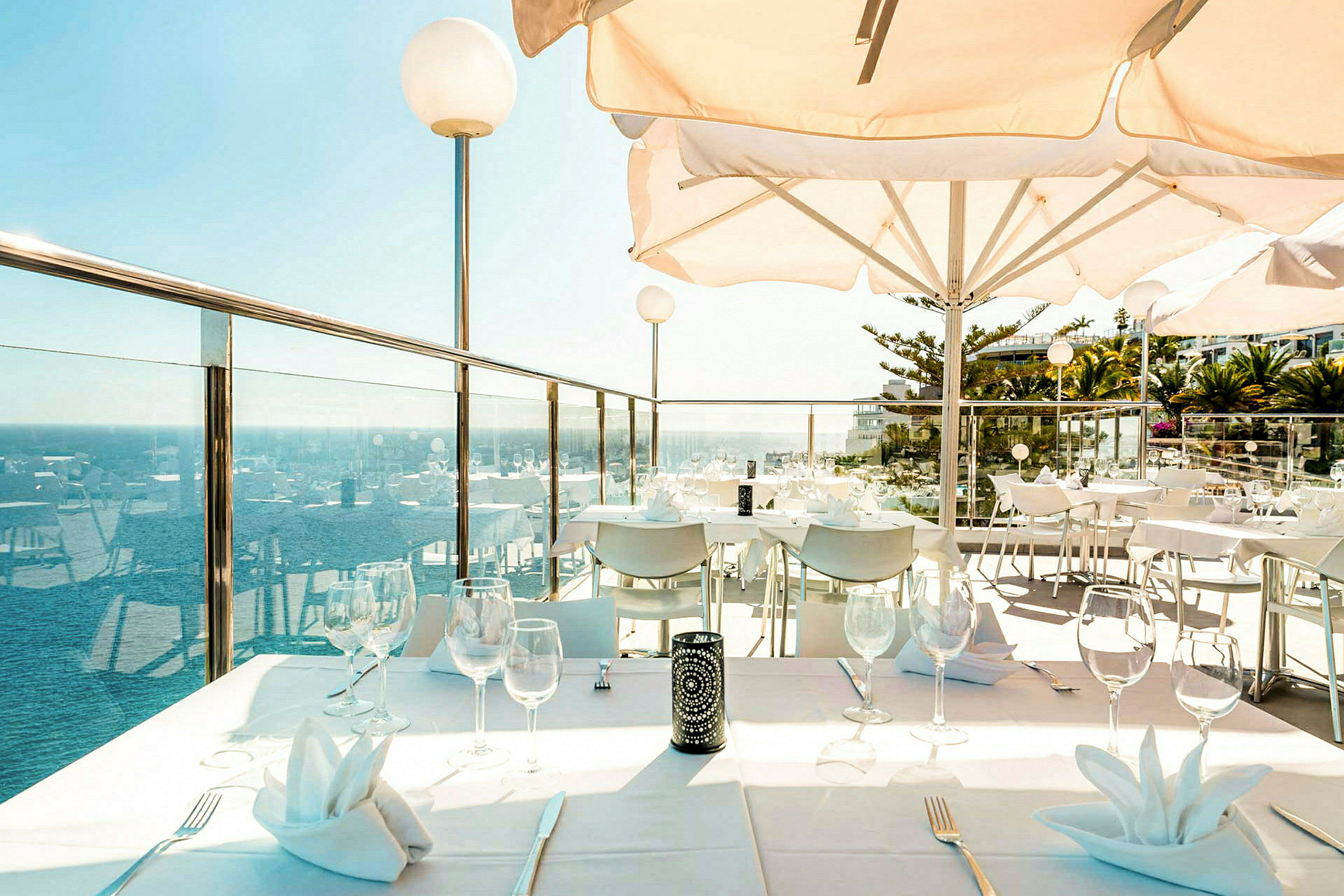 En terrasse med oprettede borde og udsigt over havet. (AI-genereret tekst)