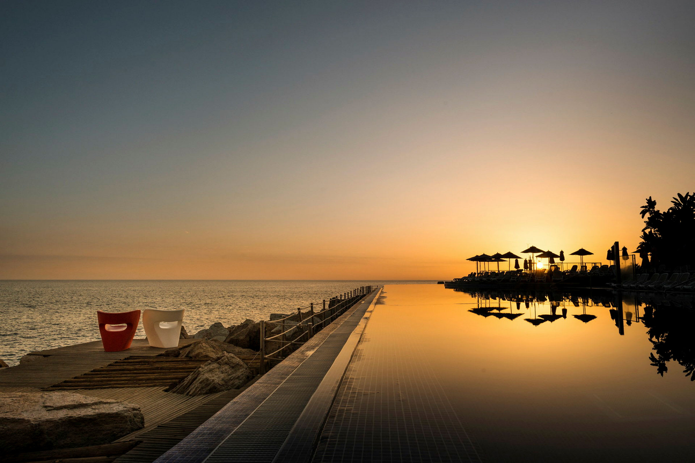 Solopgang over havet med en infinitypool i forgrunden. (AI-genereret tekst)