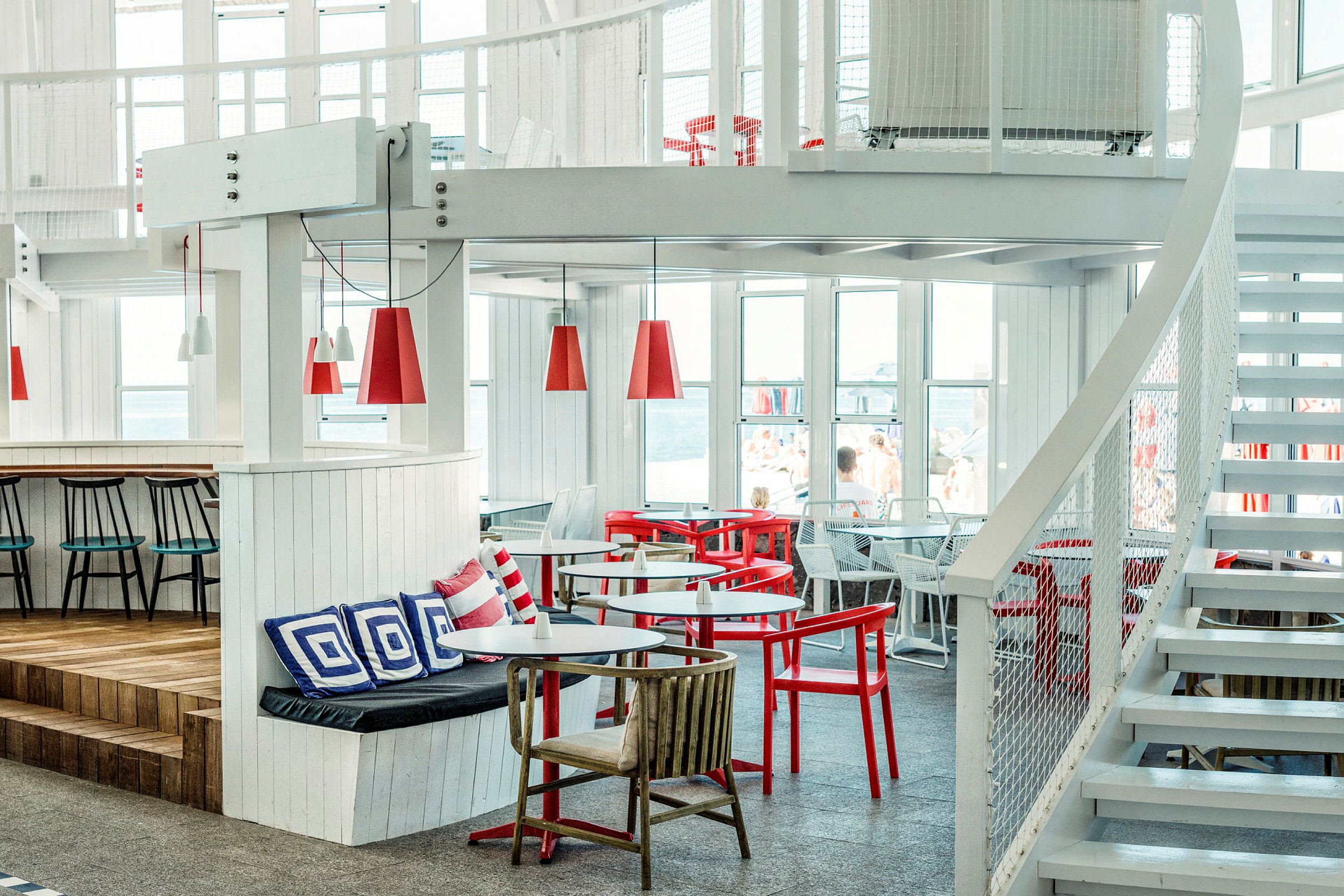 Interiør af en lys og moderne restaurant med røde og hvide møbler. (AI-genereret tekst)