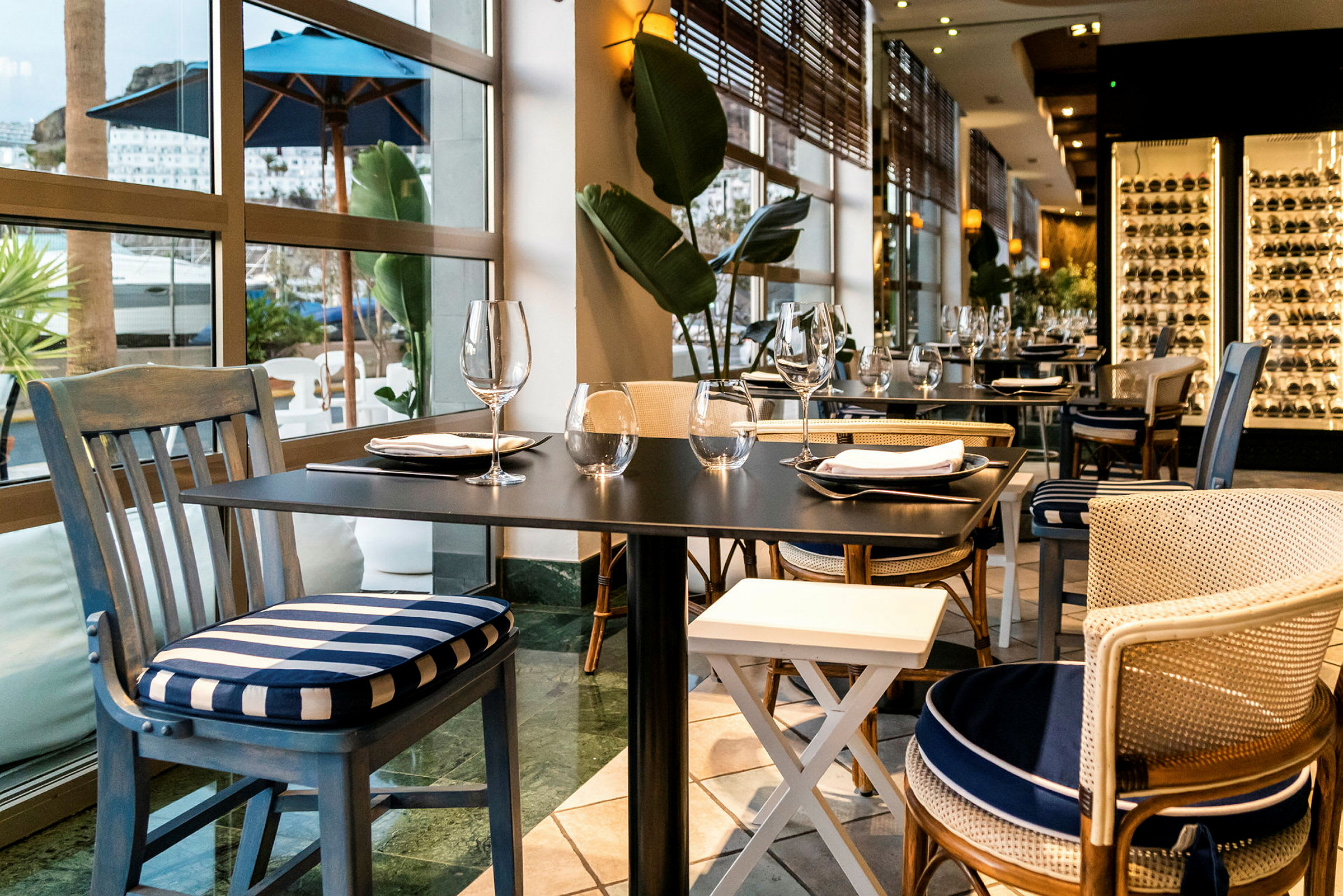 Elegant restaurant med dækkede borde og stole tæt på store vinduer. (AI-genereret tekst)