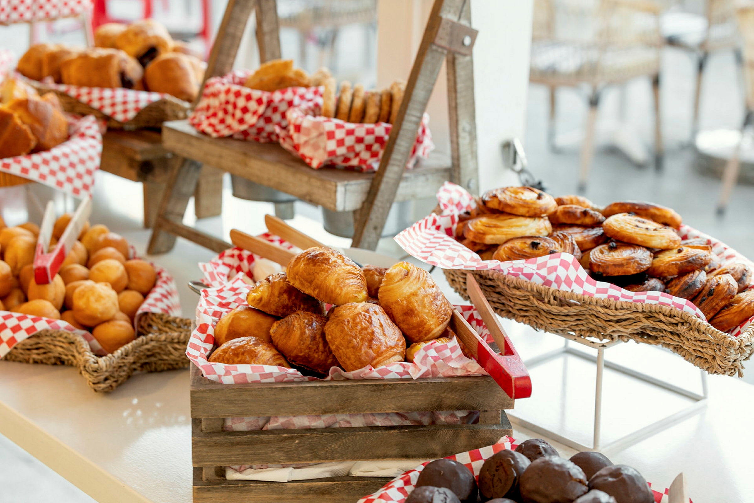En udstilling med forskellige slags bagværk, herunder croissanter, boller og danske wienerbrød, i kurve og trækasser. (AI-genereret tekst)
