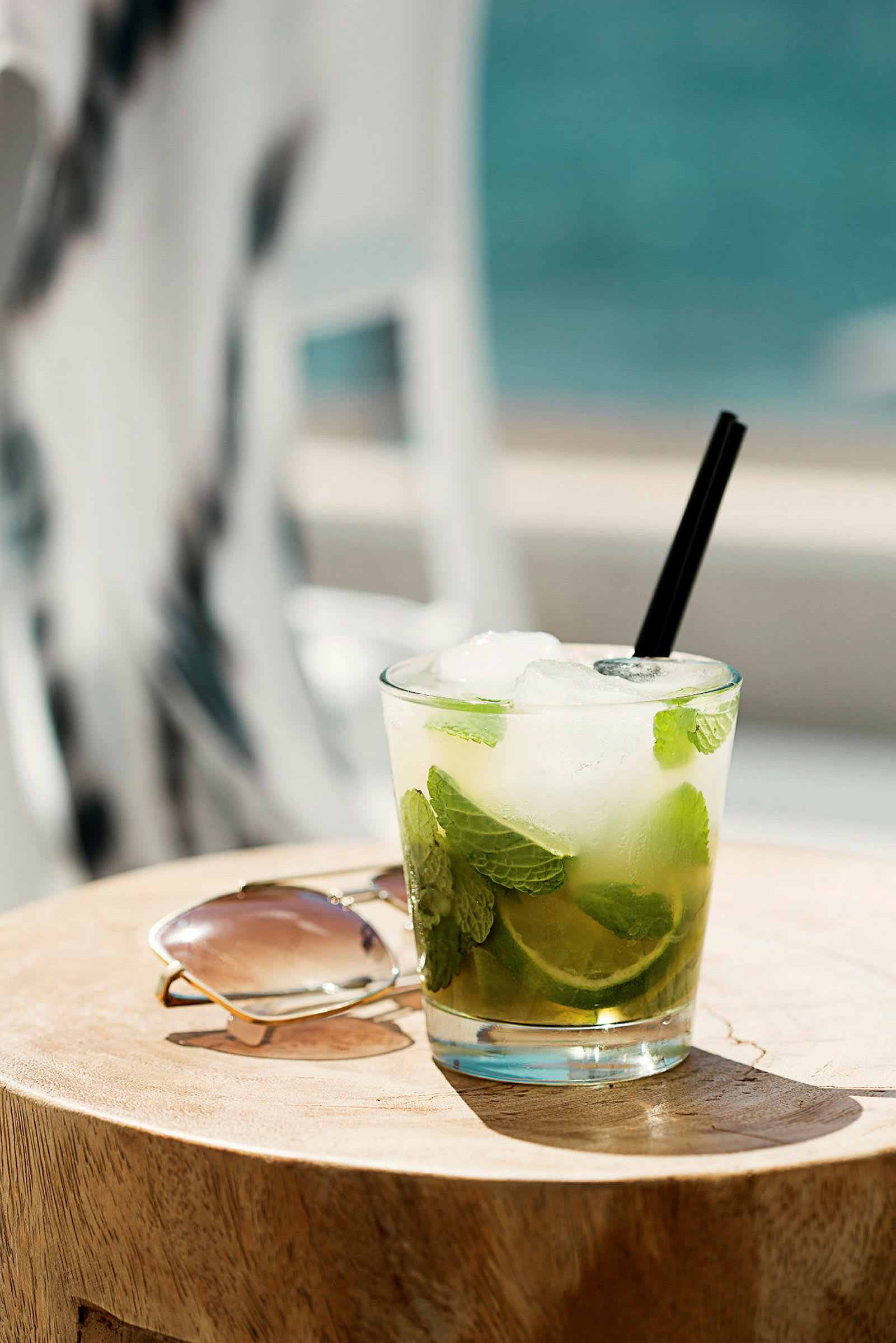 Et glas med lime og mynte ved siden af et par solbriller på et træbord. (AI-genereret tekst)